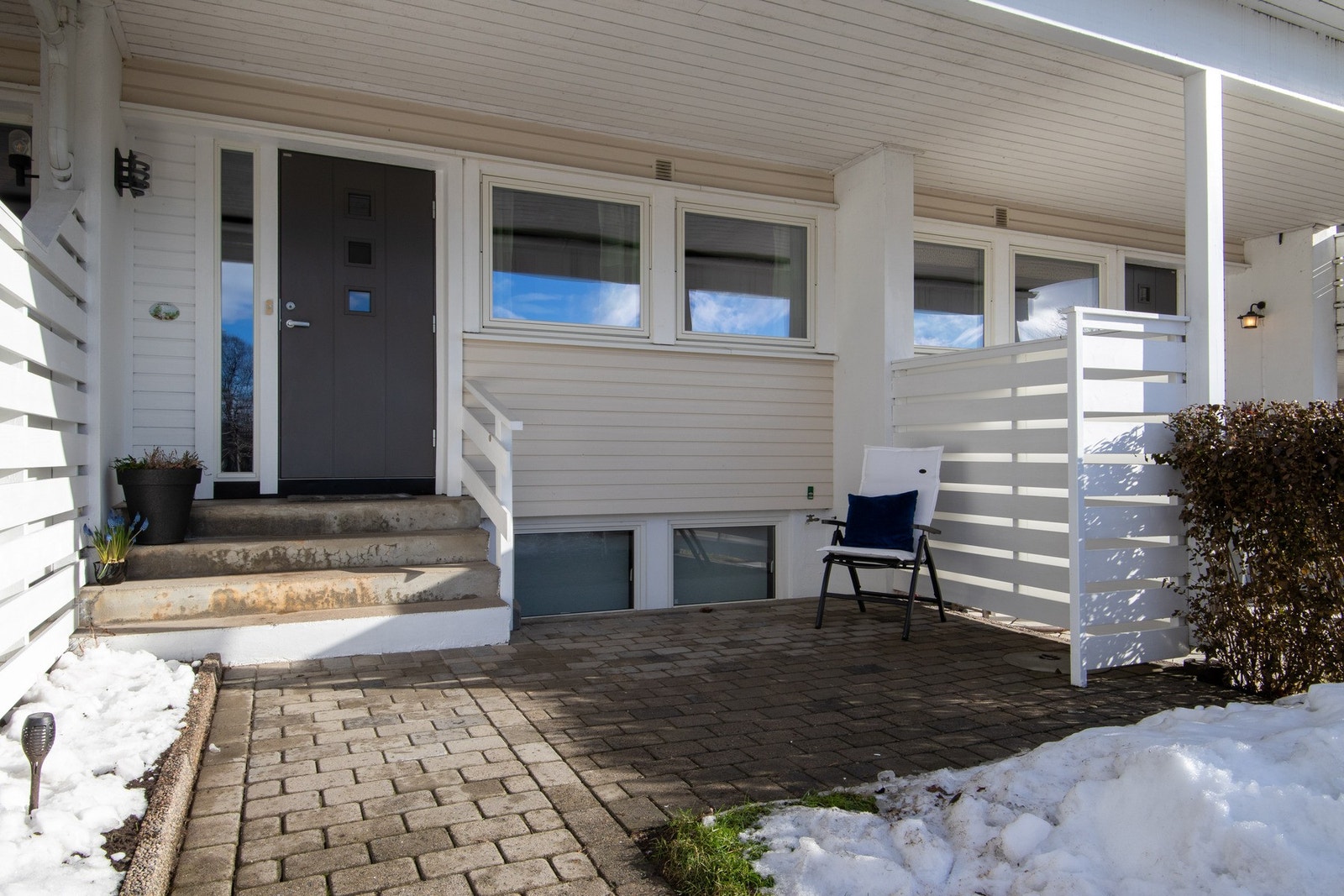 Boligen har et overbygd inngangsparti med steinbelagt adkomst og en skjermet uteplass ved inngangen. Galleribilde