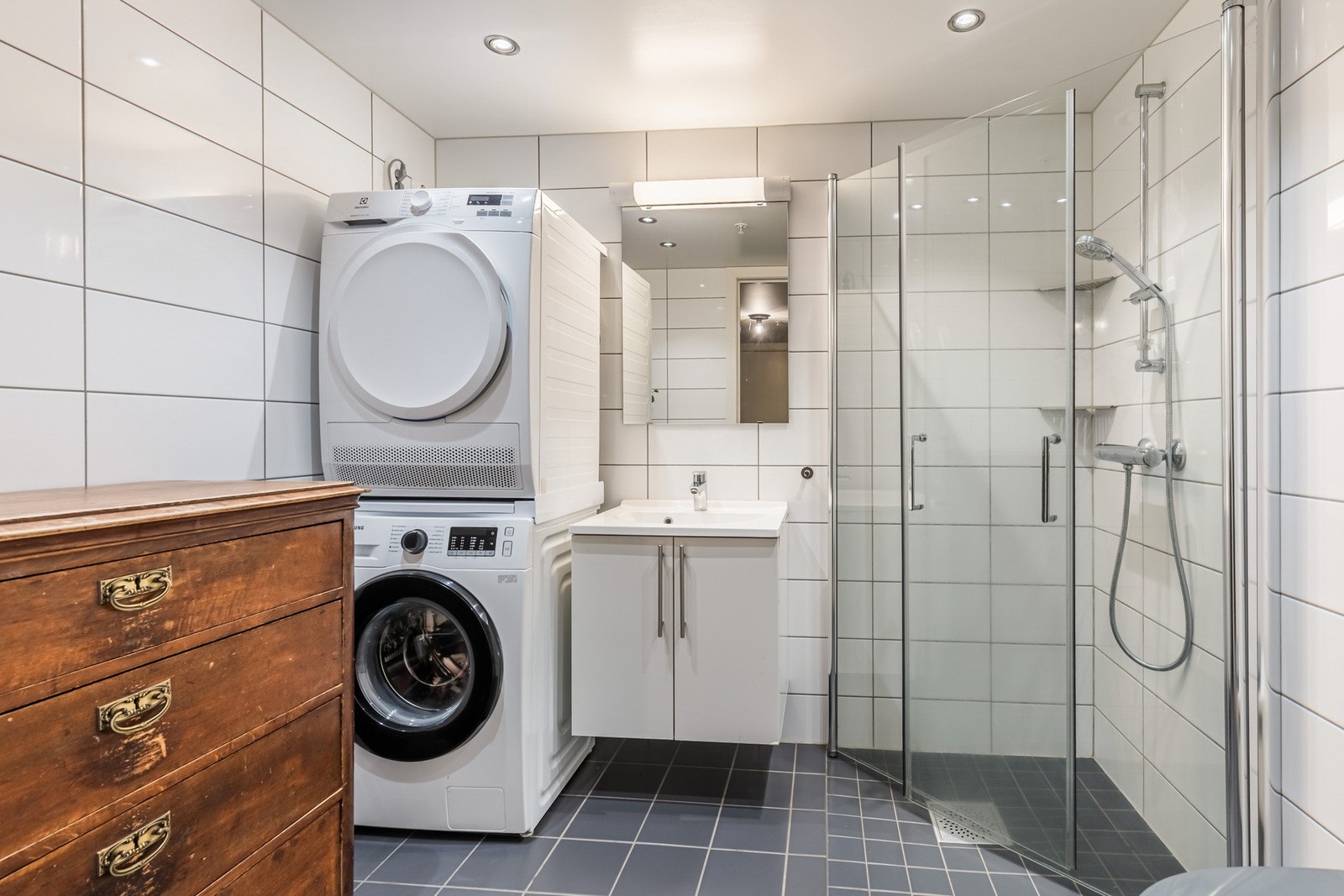 Flislagt bad fra 2017 med dusjnisje, servantinnredning med speil og vegghengt toalett med innebygget sisterne. Galleribilde