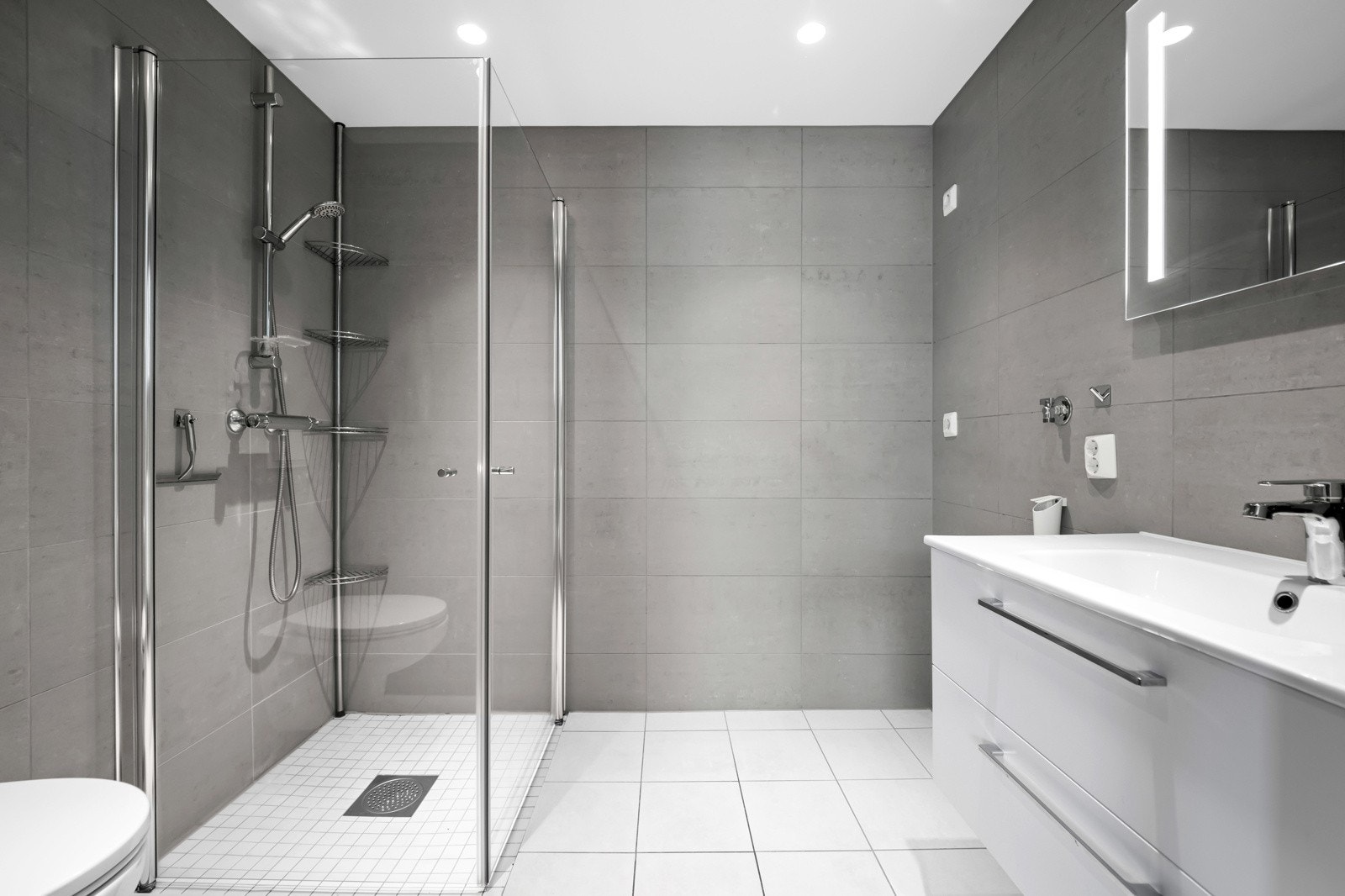 Adkomst fra hovedsoverommet til et flislagt og delikat baderom med behagelig gulvvarme og opplegg for vaskemaskin. Galleribilde