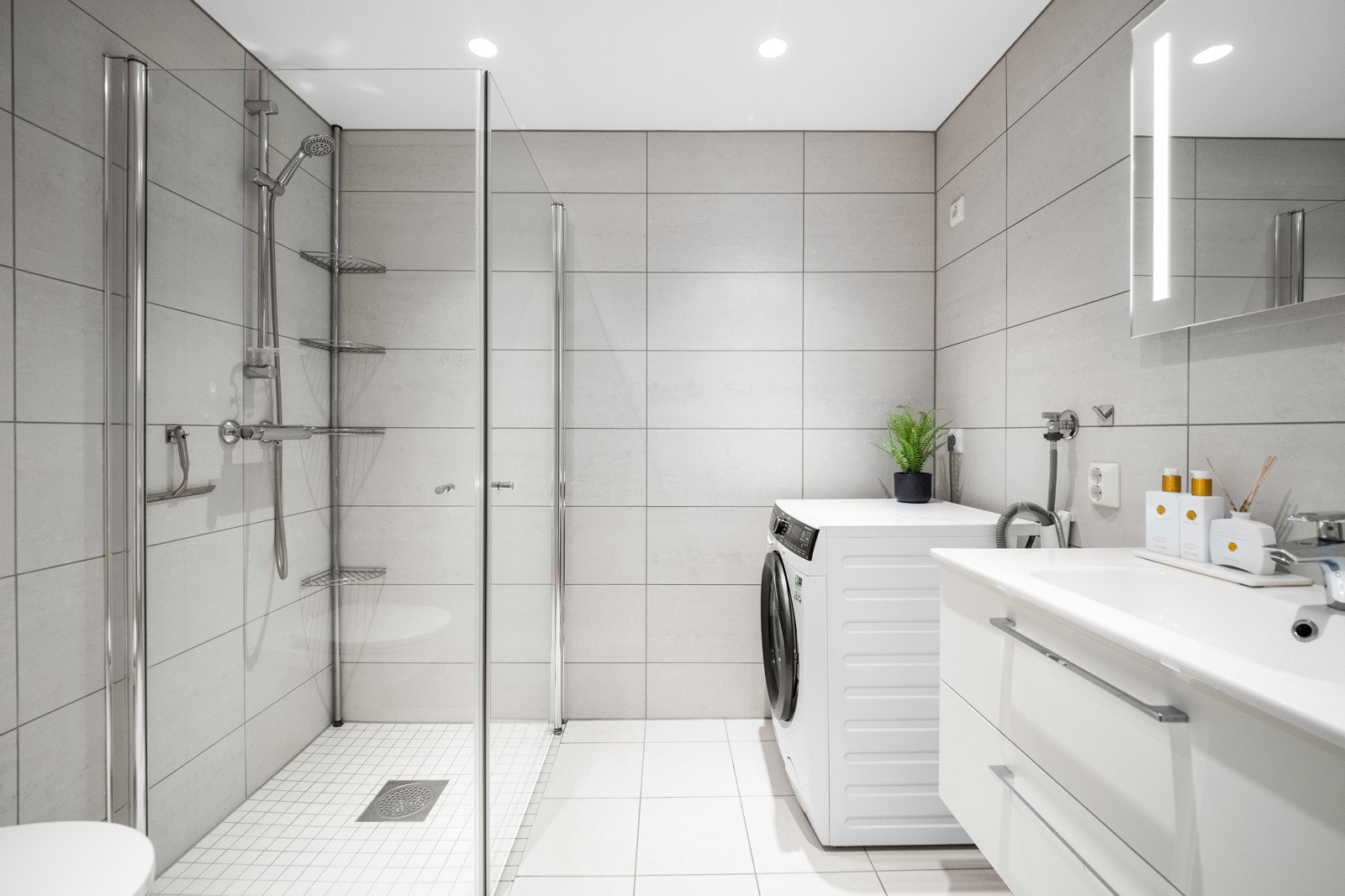 Boligens andre bad med adkomst fra entré. Lagt med store og delikate fliser, og med gulvvarme og opplegg for vaskemaskin. Galleribilde