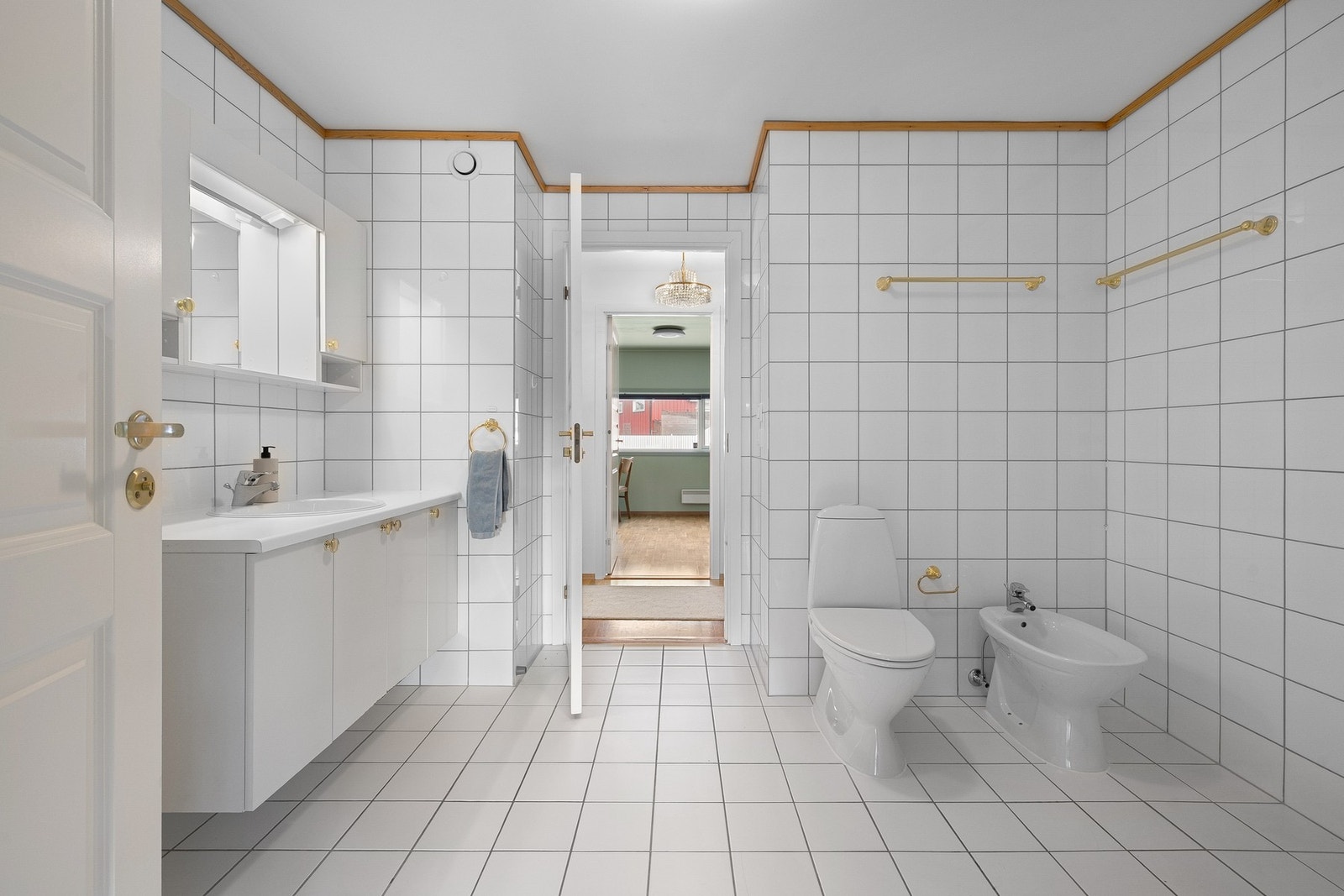 Pent flislagt bad som er utstyrt med dusjkabinett, klosett, servant, overskap med speil samt opplegg for vaskemaskin og varmtvannsbereder. Galleribilde