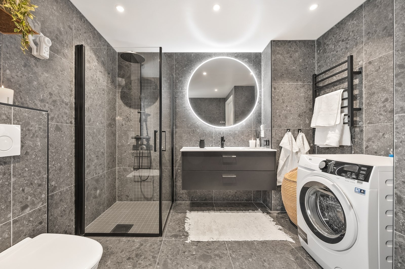 Her er det varmekabler i gulvet, belyst speil og praktisk opplegg for vaskemaskin. Galleribilde