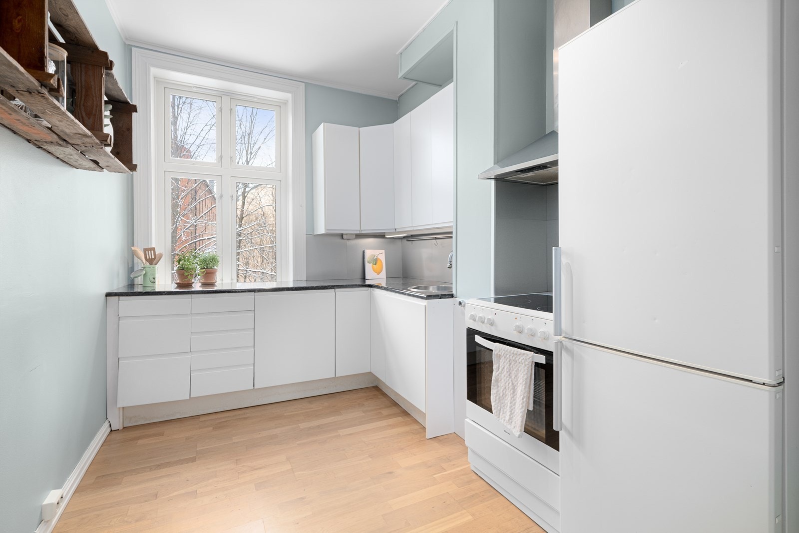 Separat kjøkken med utsyn mot bakgården. Lyse, glatte fronter og hvitevarer som medfølger. Galleribilde