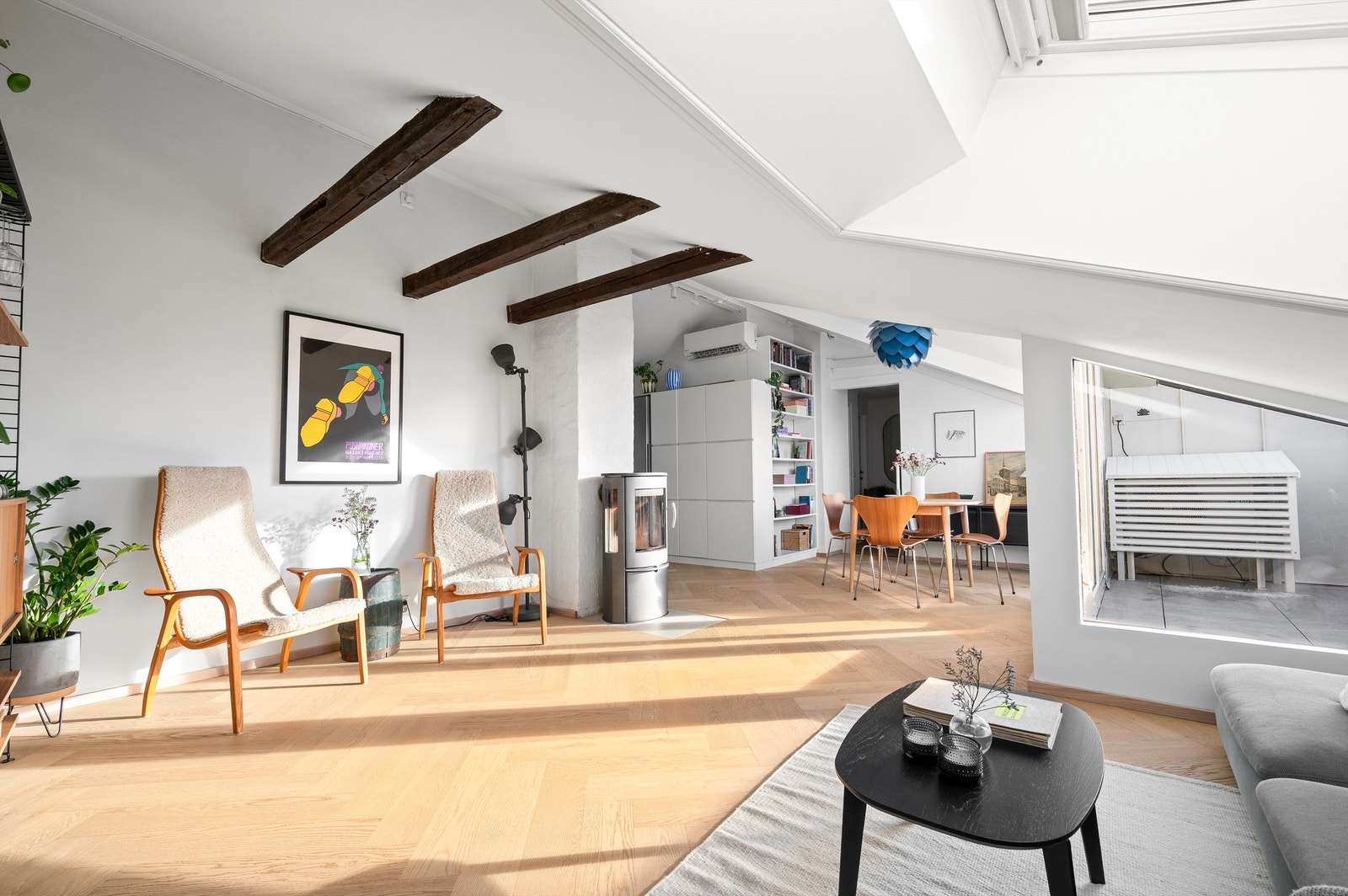 Synlige takbjelker gir rommet karakter og understreker den åpne følelsen mot spiseplass og kjøkken. Galleribilde