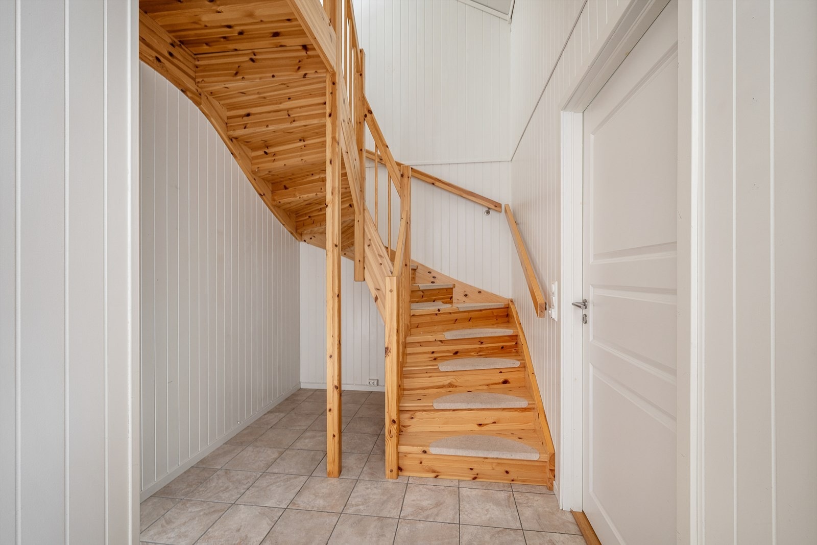 En lakkert tretrapp med spilerekkverk leder opp til andre etasje. Galleribilde