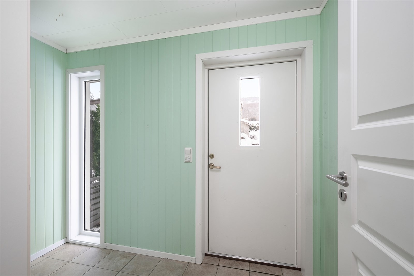 Inngangspartiet er et lyst vindfang med flislagt gulv og behagelig gulvvarme. Galleribilde