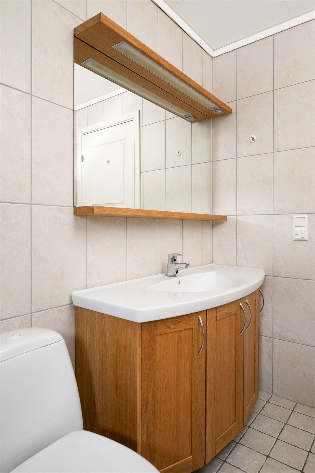 Baderomsinnredning med profilerte fronter, nedfelt servant og et praktisk dusjhjørne. Galleribilde