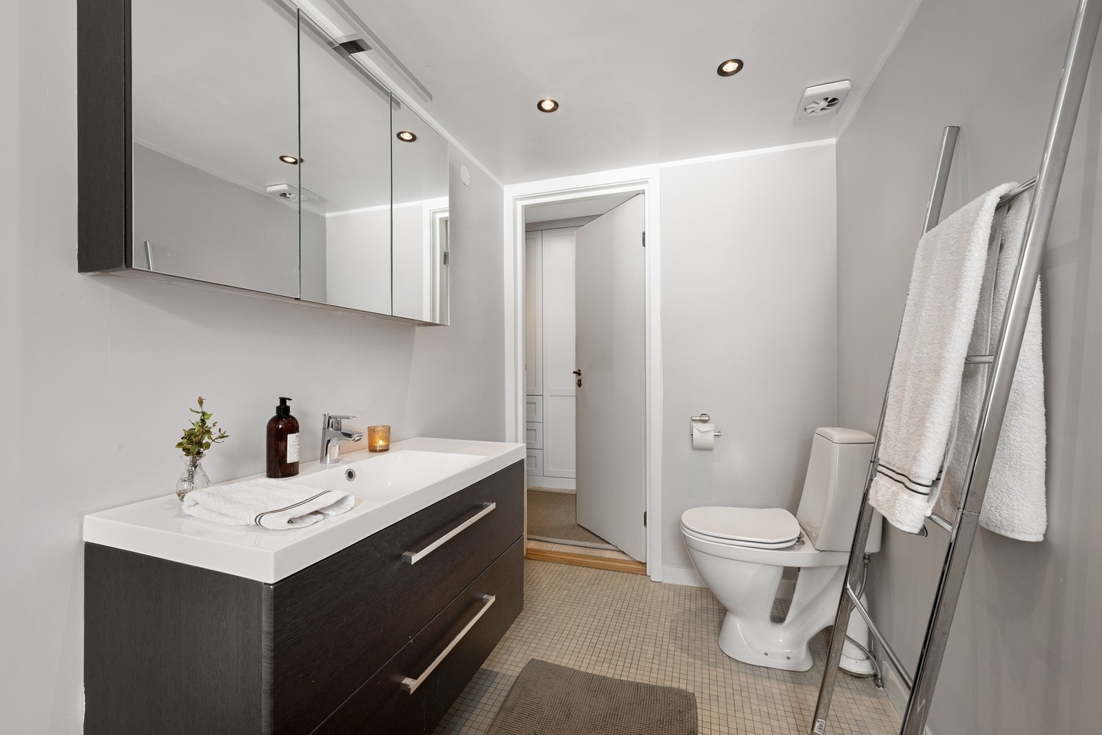 Baderomsinnredning bestående av benkeskap med glatte fronter.
Veggskap med speilfronter over servant. Galleribilde