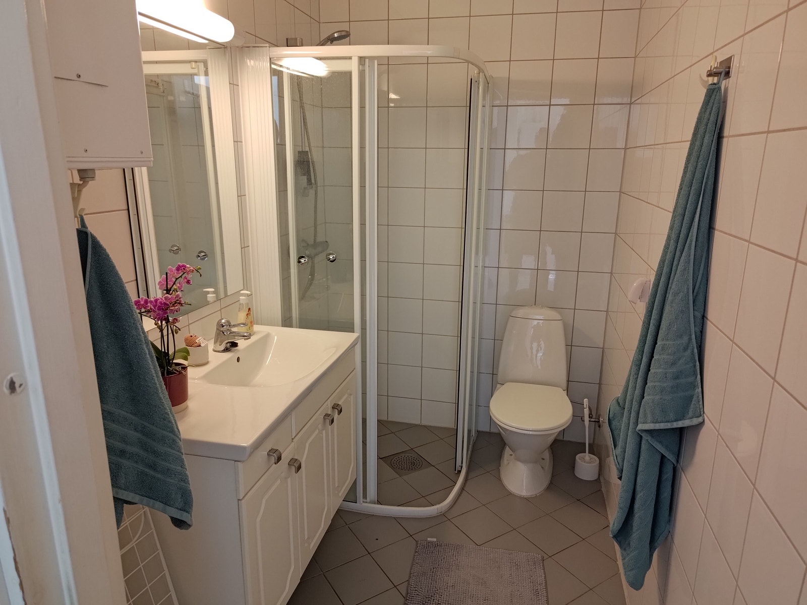 Stort flislagt bad med servantskap, dusj og wc. Galleribilde