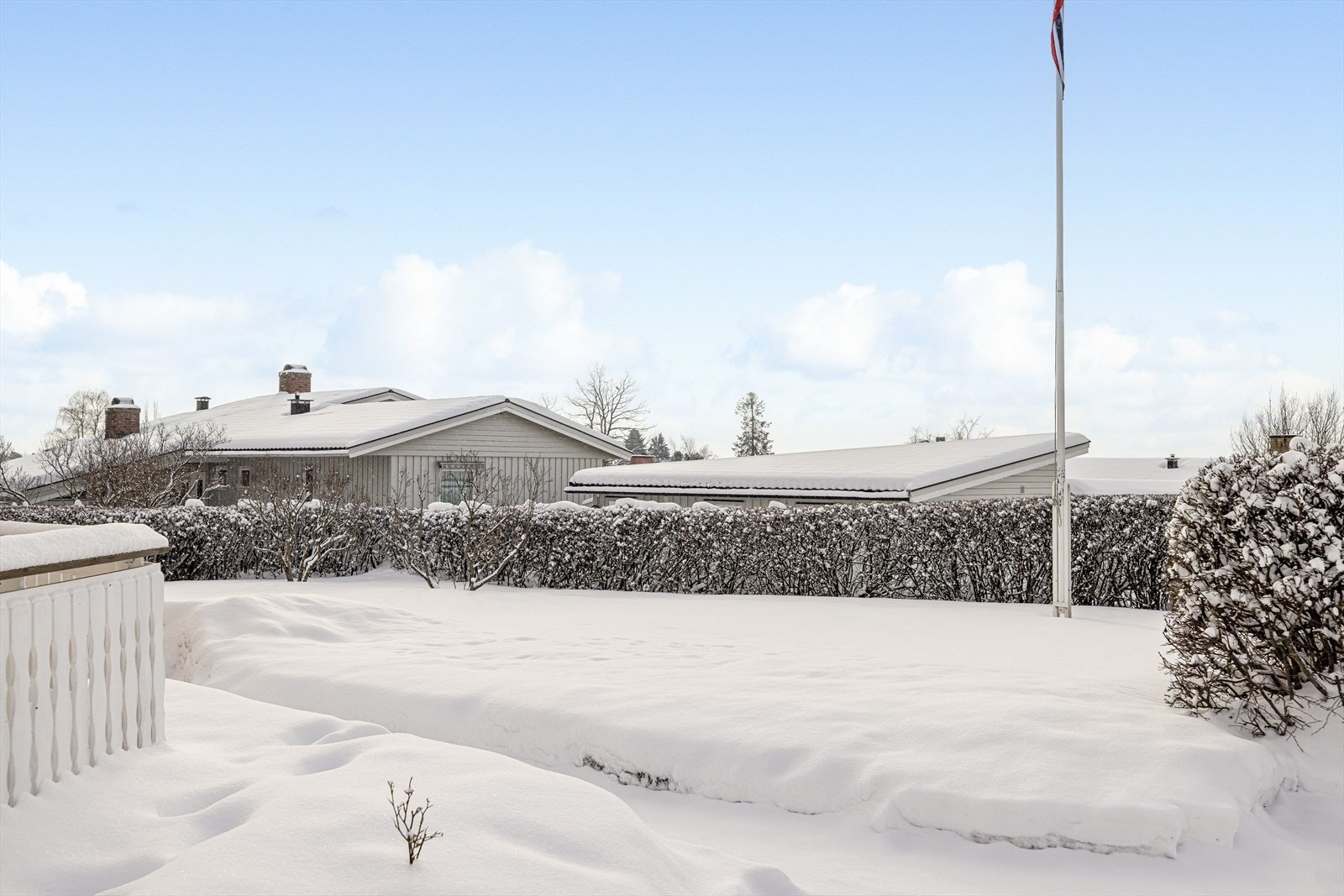 Fra terrassen er det trapp ned til romslig hage som er pent opparbeidet med plen, beplantning, hekk og flaggstang. Galleribilde