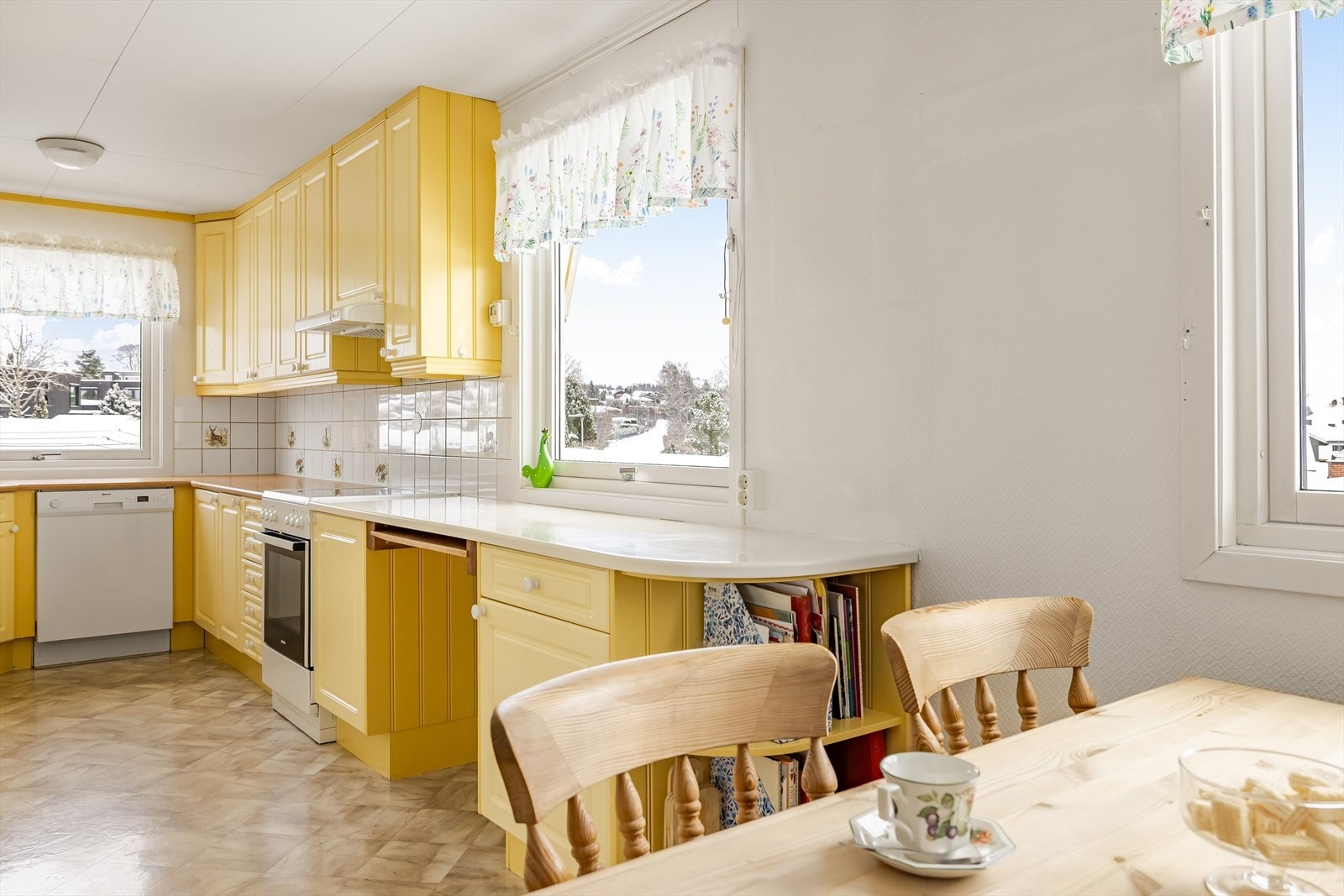 Kjøkkenet har belegg på gulv, lysmalte overflater og tre vinduer som slipper inn rikelig med naturlig lys. Galleribilde