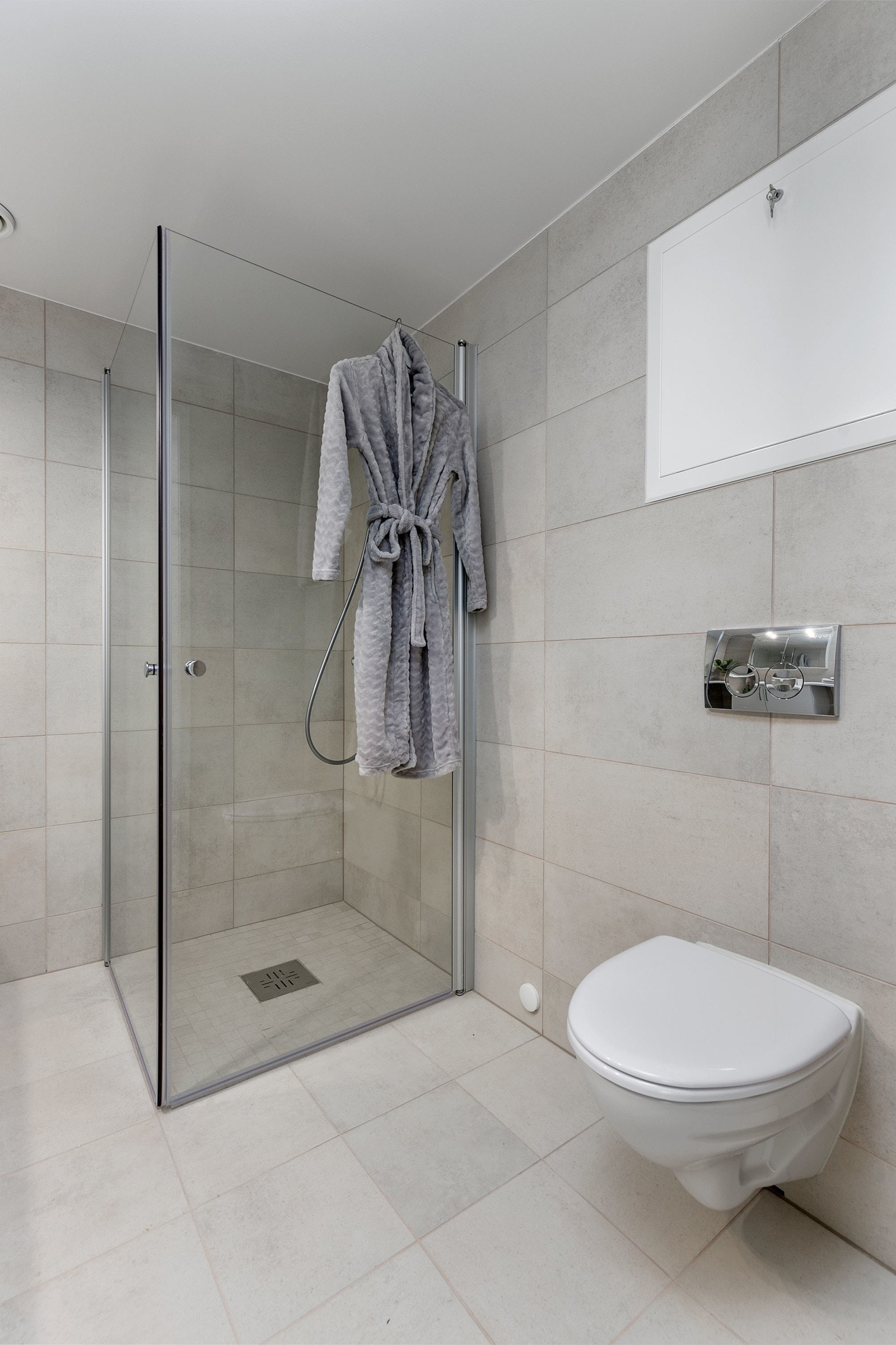 Badet har vegghengt toalett med innbygget sisterne, servant med skapinnredning samt speil med belysning Galleribilde