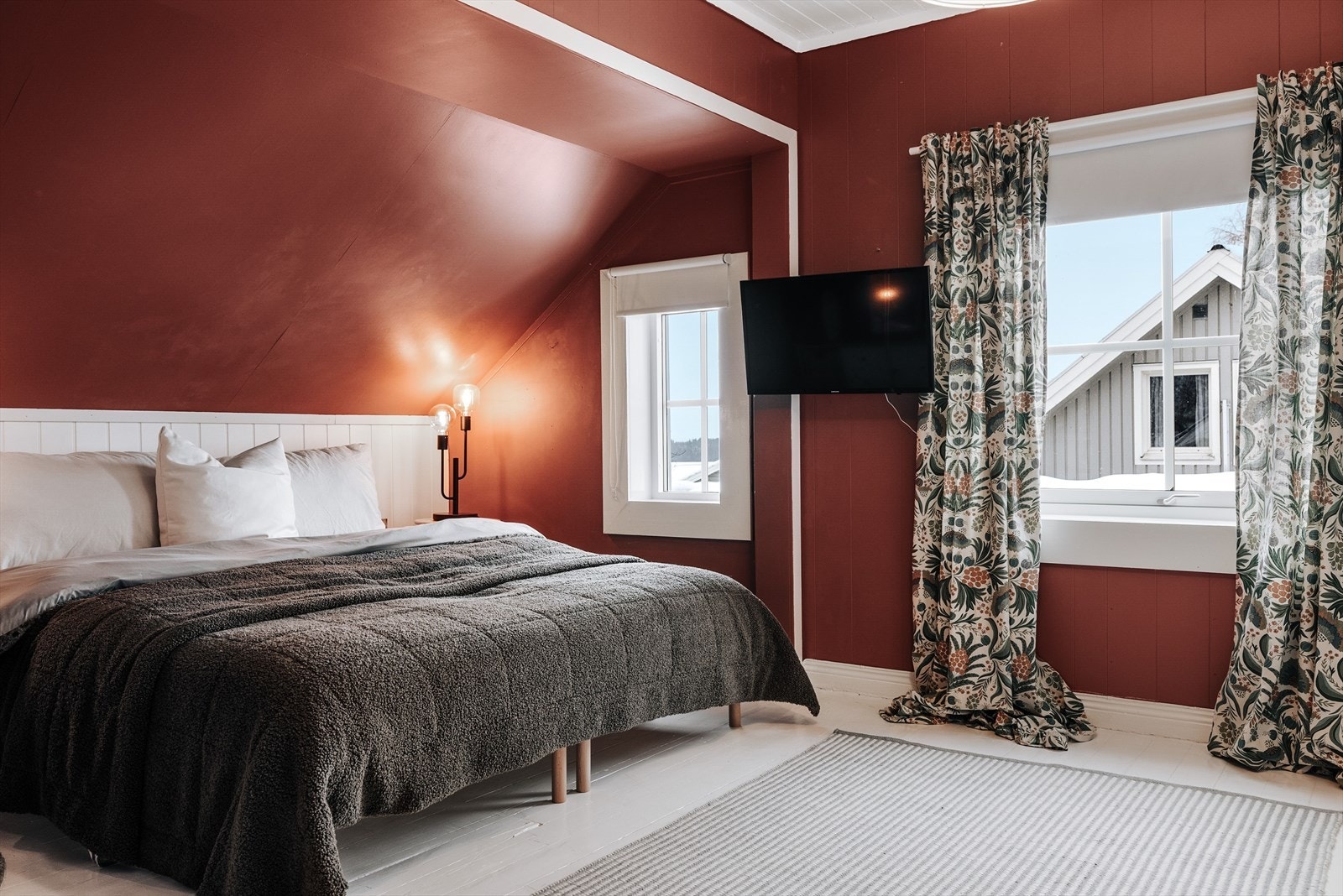 Soverom nummer to er malt i en dyp rødfarge med en lysere kontrastvegg bak senga. På gulvet er det malt tregulv. Galleribilde