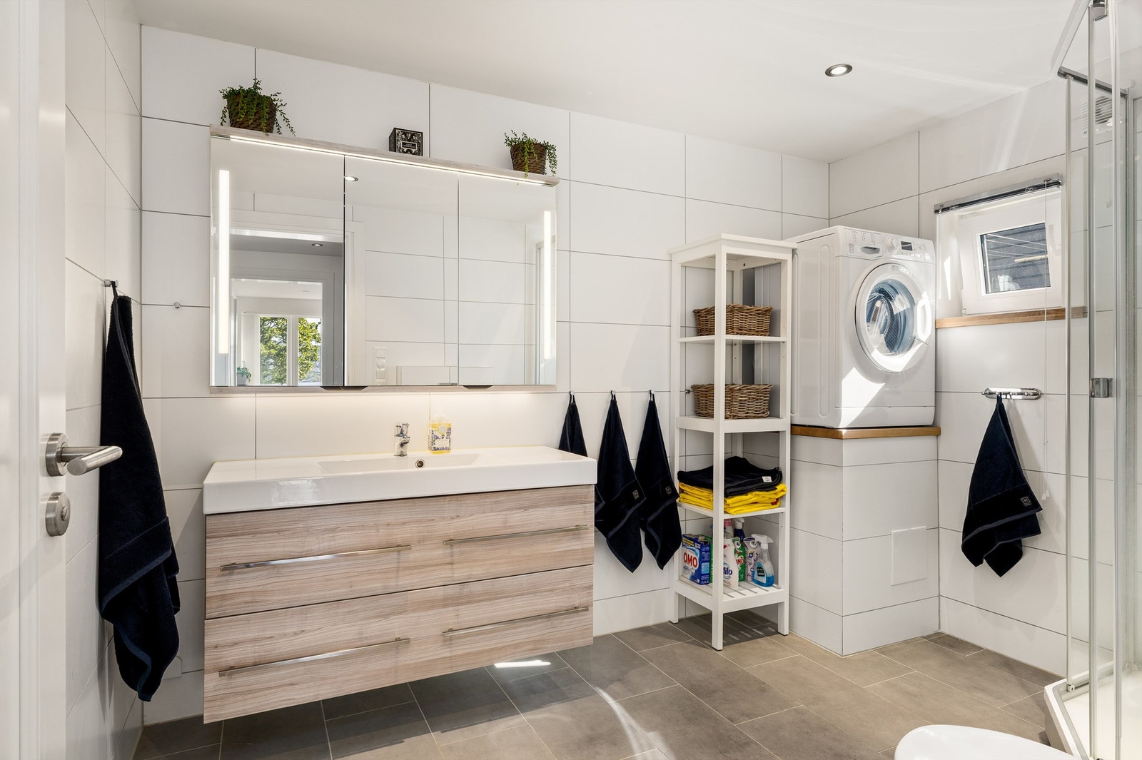 Badet har samme overlate og farge som gulvflisene i entrén, men her er det rektangulære, noe som bidrar til at rommet virker større. Galleribilde