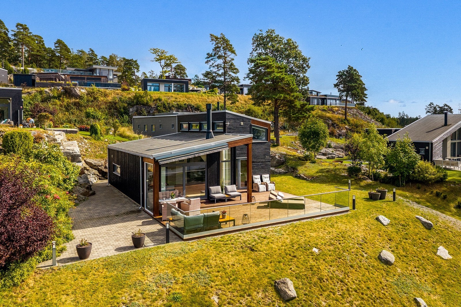 MOT SJØEN: Hagen er variert og flott beplantet med terrasse og platting. Galleribilde