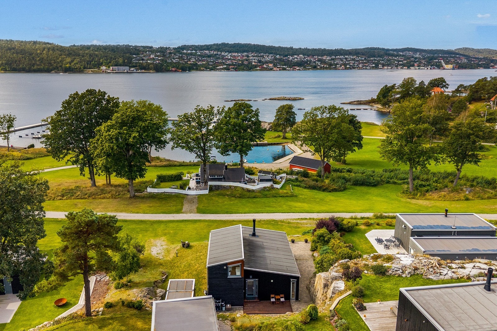 Den sortmalte funkishytta ligger åpent og fint i fremste rekke med utsikt utover sjøen. Galleribilde