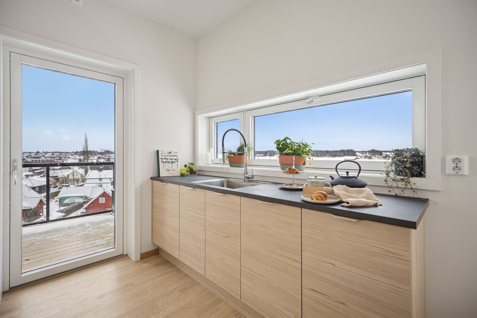 Detalj fra kjøkkenet med nedfelt oppvaskkum i rustfritt stål og ett-greps blandebatteri. Galleribilde