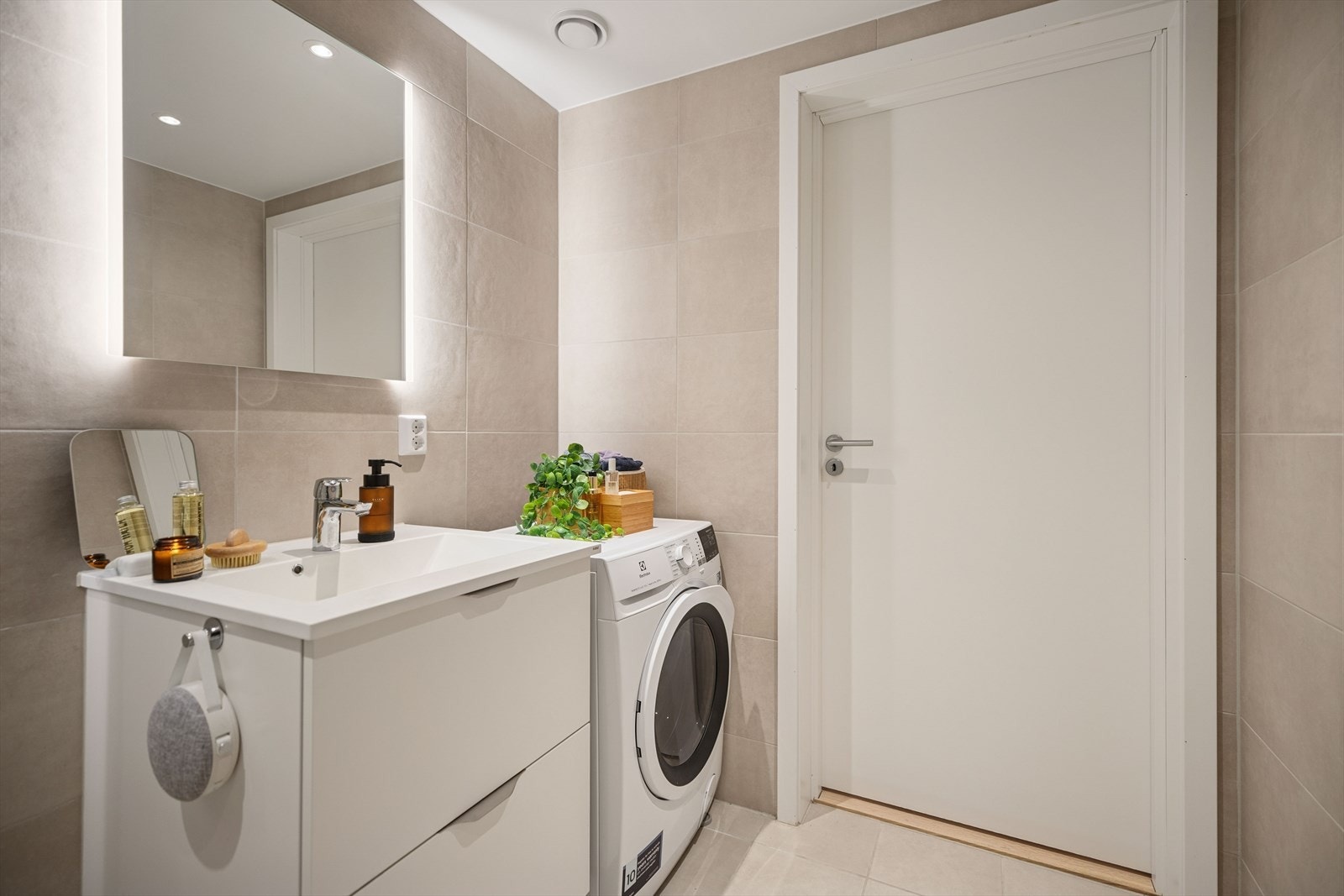 Her er det opplegg for vaskemaskin og en stilren baderomsinnredning med heldekkende servant. Galleribilde