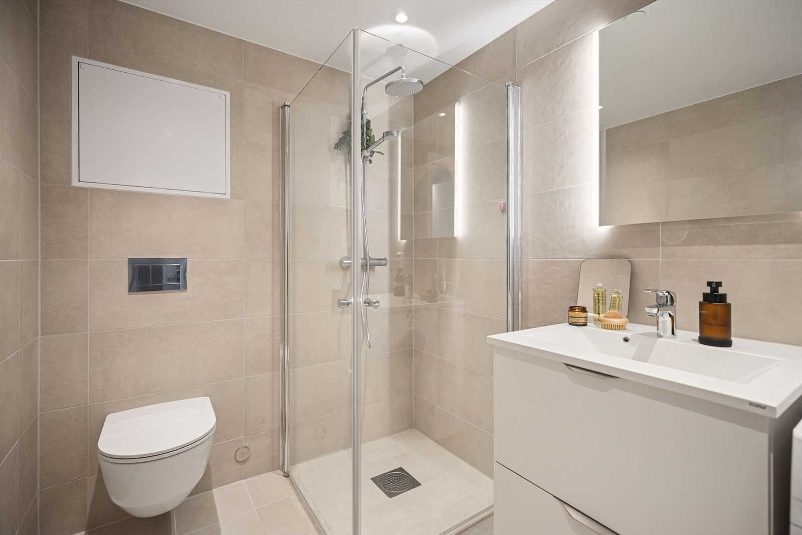 Badet er utstyrt med veggmontert toalett og et praktisk dusjhjørne med innfellbare glassdører. Galleribilde