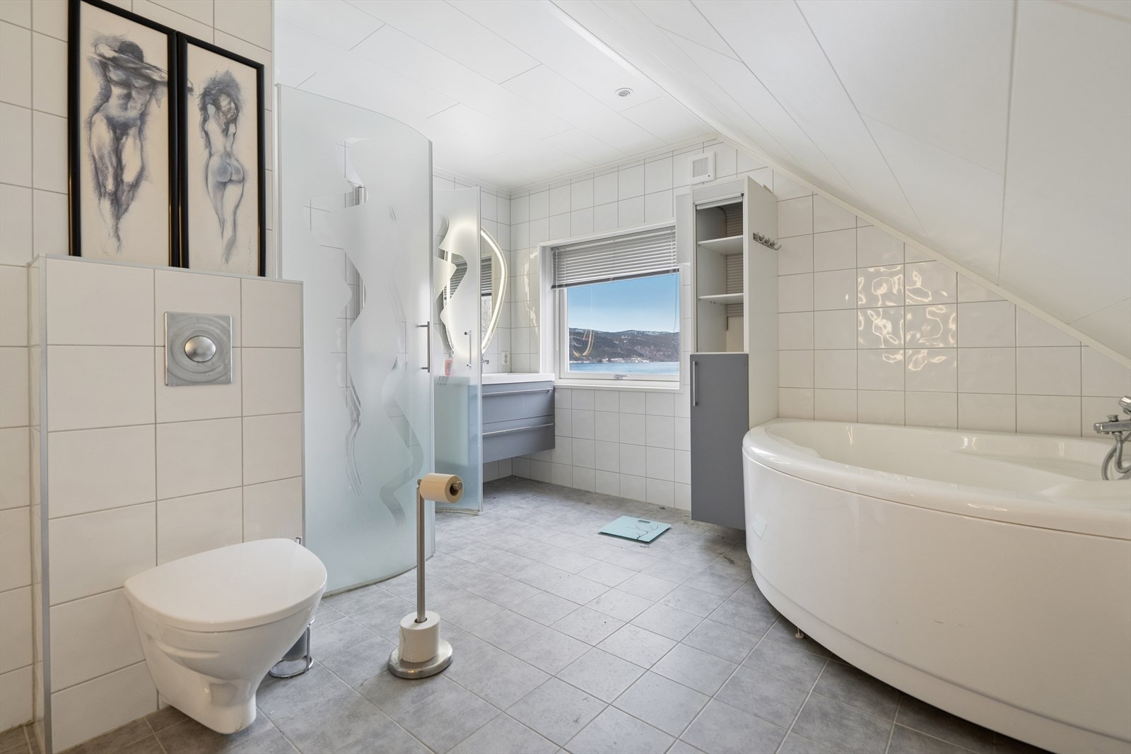 Badet er en romslig variant med to separate servanter, hjørnekar, dusjhjørne, toalett og opplegg til vaskemaskin. Galleribilde