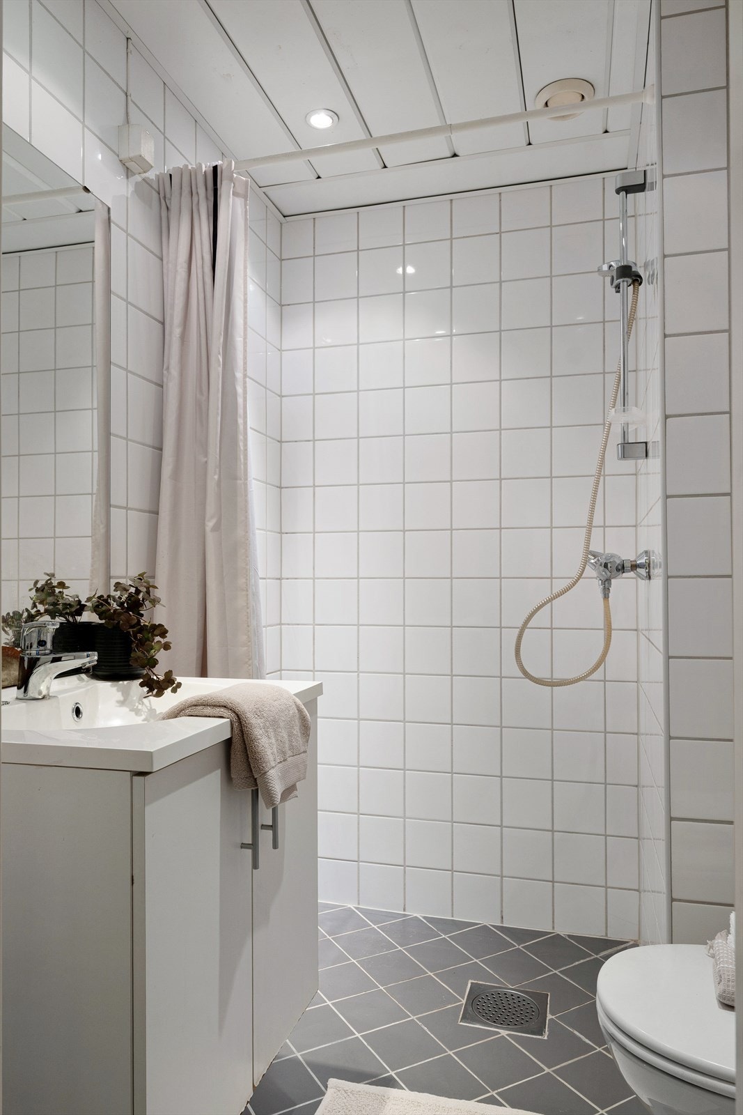 Badet er utstyrt med dusjhjørne, naturlig avtrekk, stoppekran, servant, servantskap og wc Galleribilde