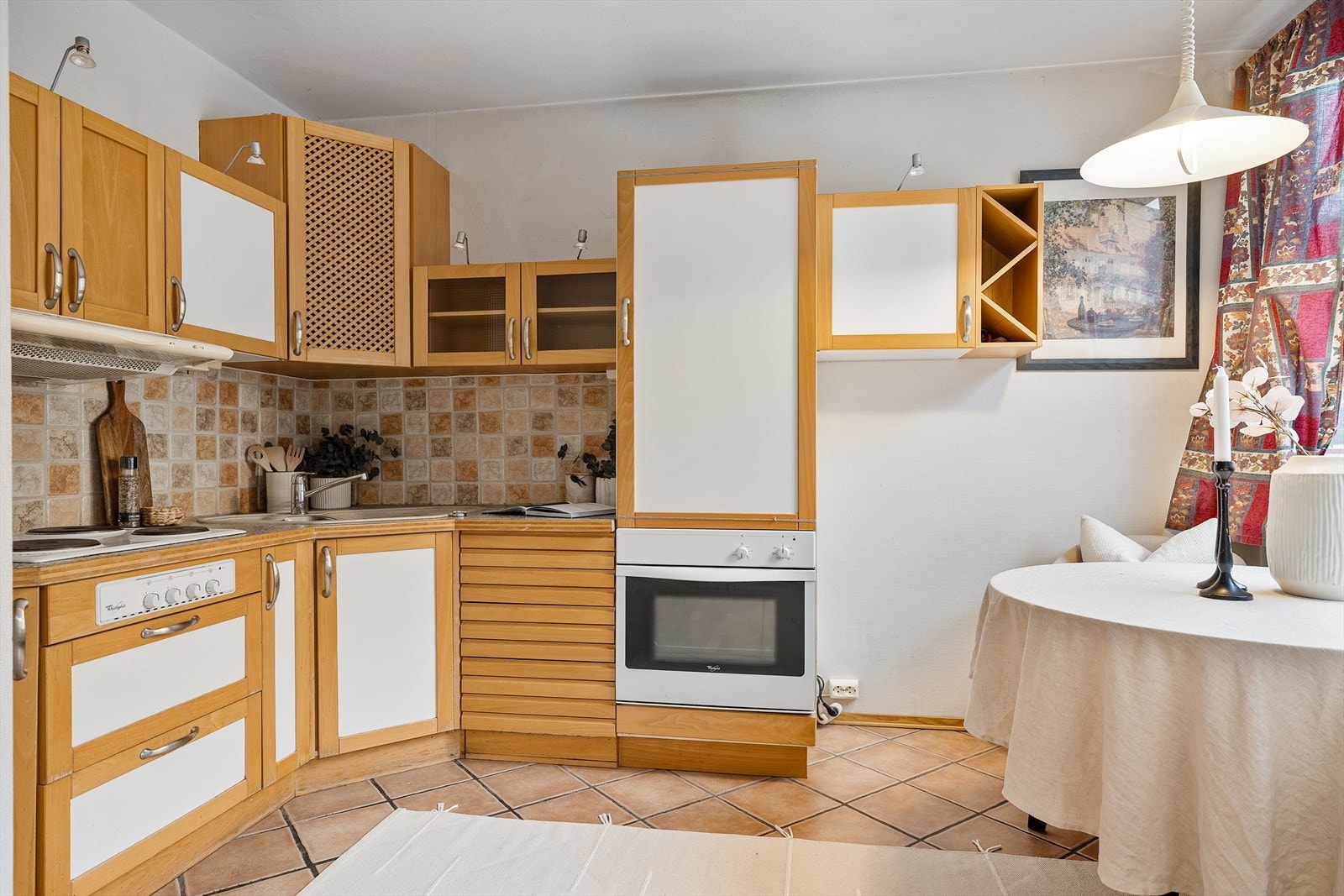 Profilert kjøkkeninnredning med malte fronter og benkeplate med nedfelt koketopp og oppvaskkum av stål Galleribilde