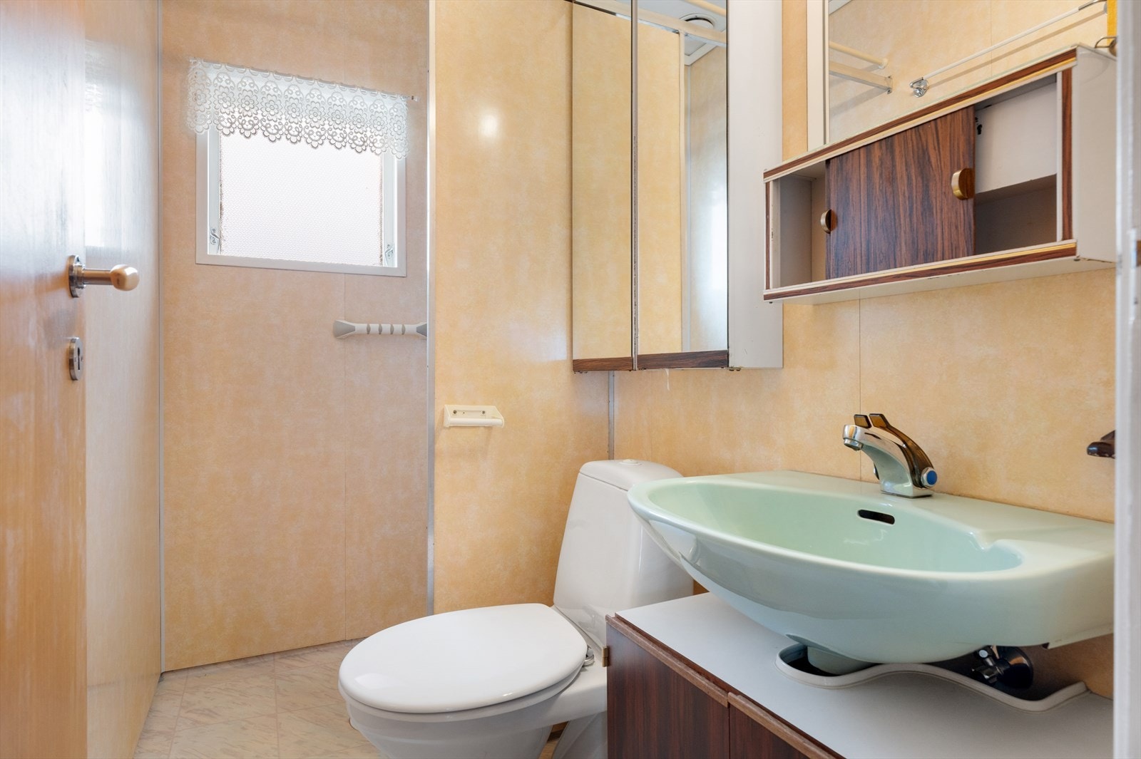 Bad innredet med servant, speilskap, toalett og dusj med forheng. Galleribilde