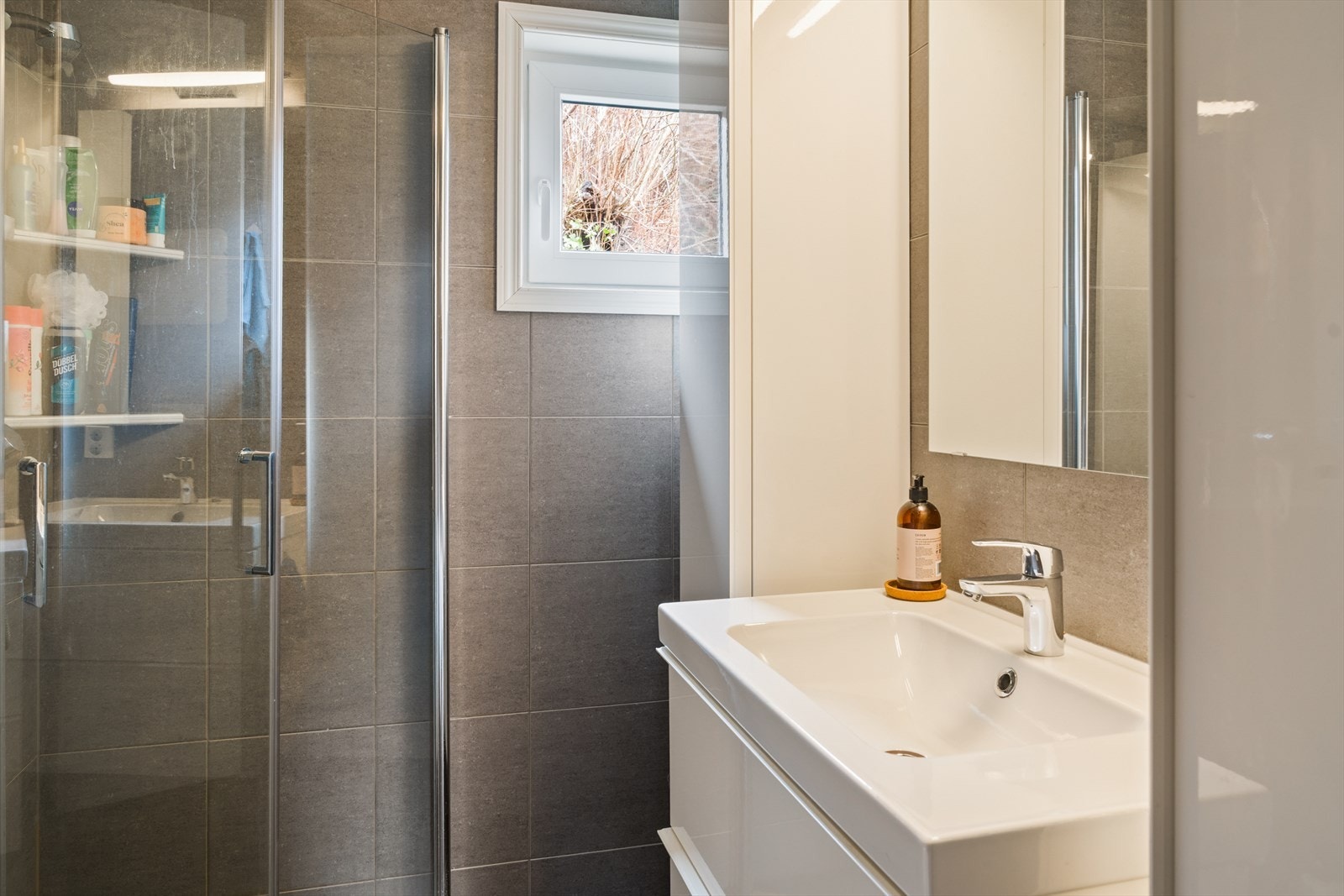 Badet inneholder innredning med nedfelt servant, vegghengt toalett og dusjvegger Galleribilde