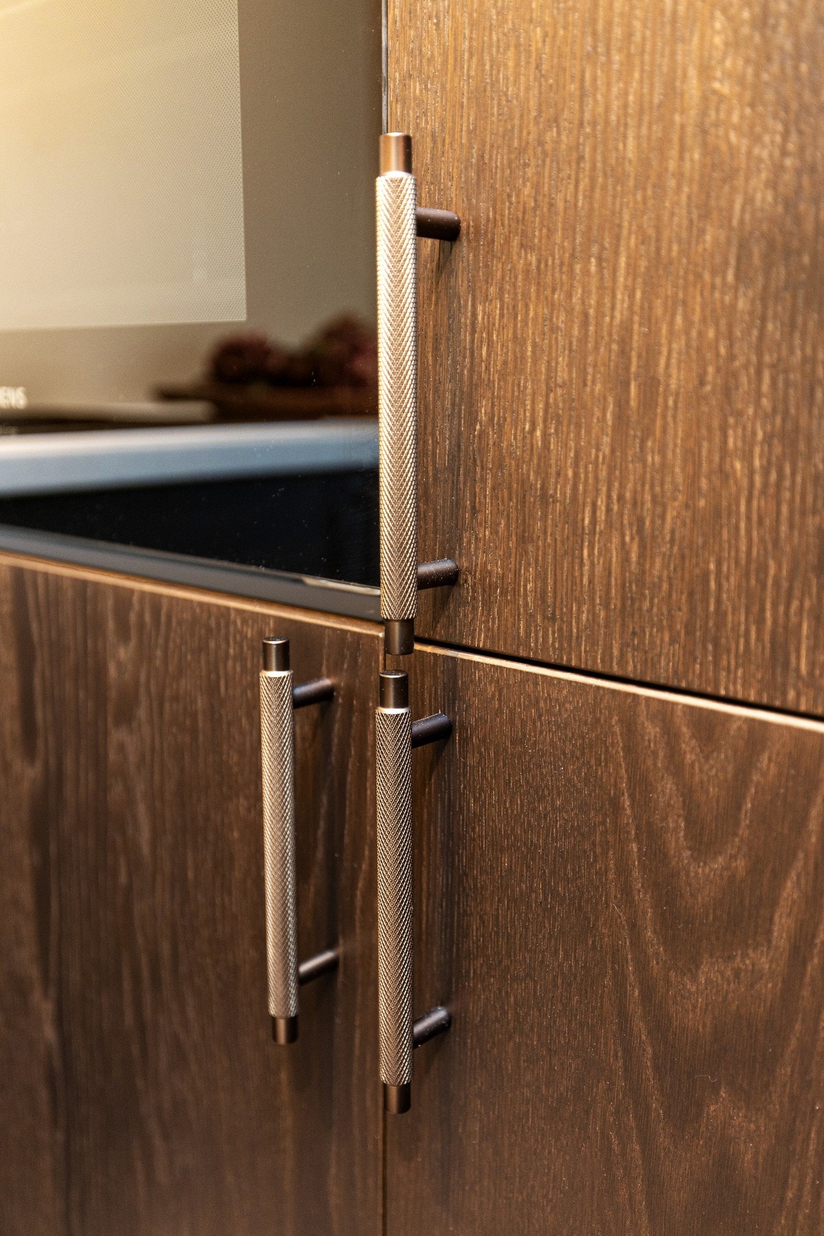 Håndtak som komplementerer de eksklusive walnut eikefinér frontene på kjøkken. Galleribilde