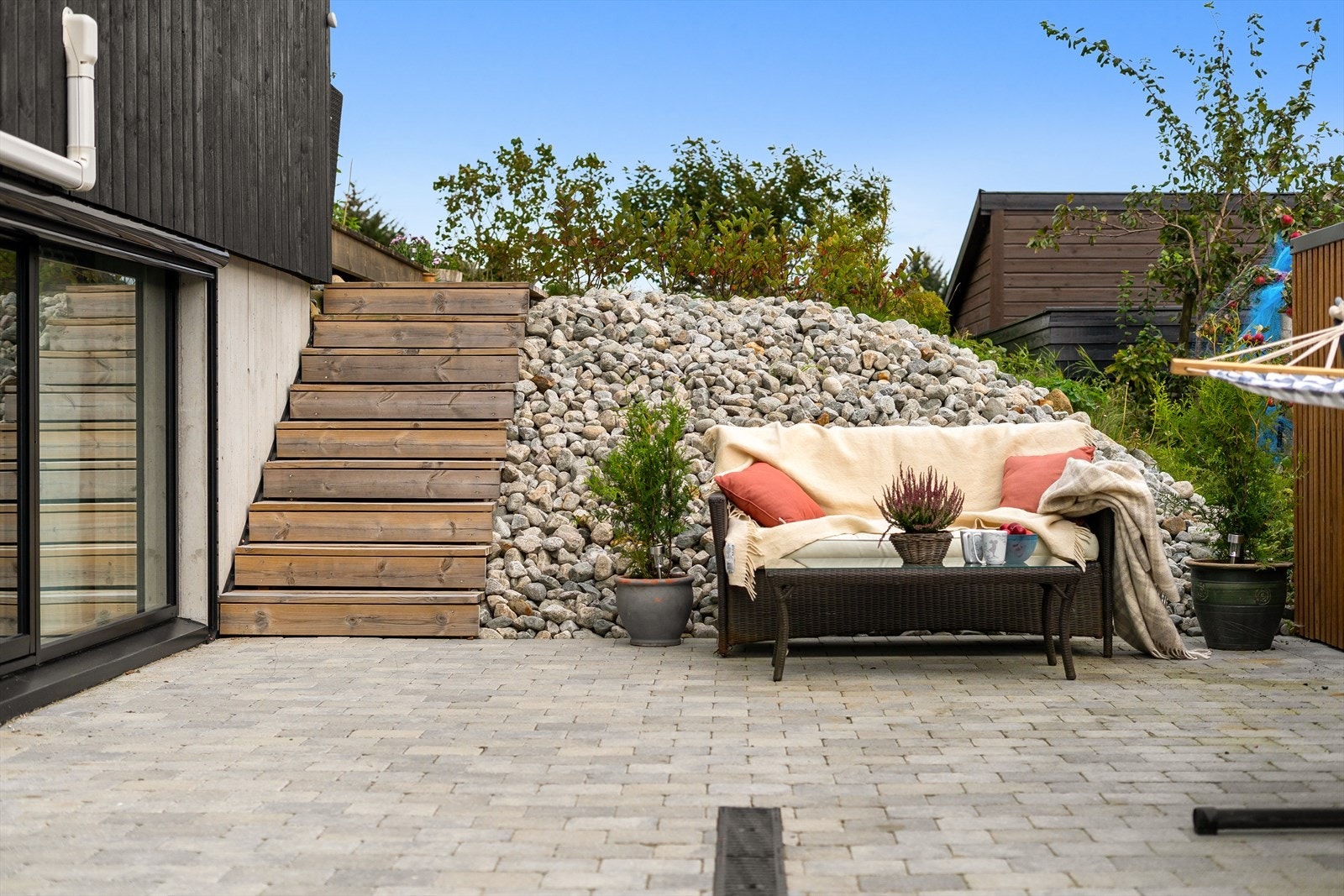 Nedsenket hage med belegningsstein og fin beplantning. Det er montert automatisk utvendig solskjerming på alle vinduer som vender mot sør. Galleribilde