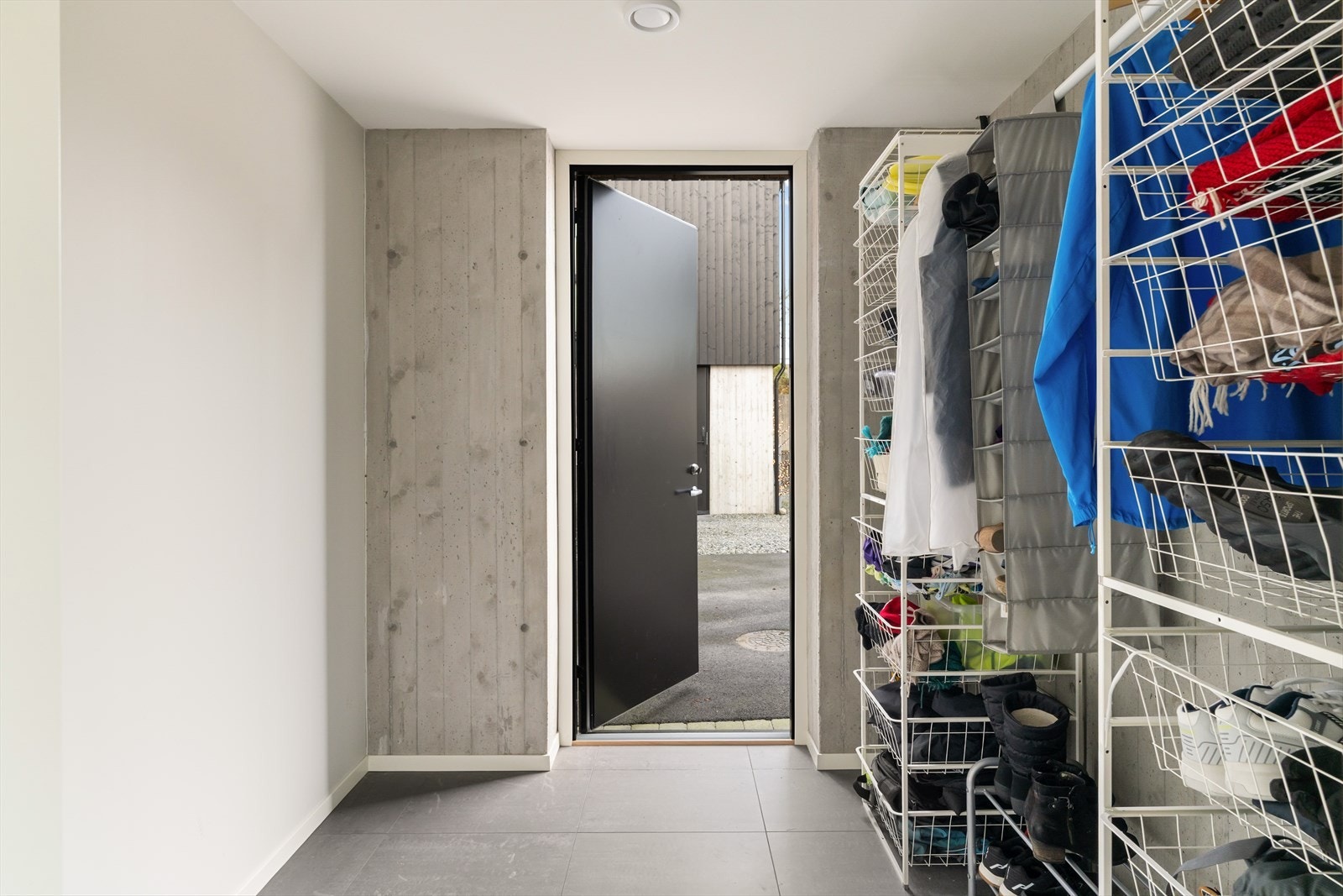 Bi-inngang med fliser på gulv og plass til oppbevaring av yttertøy og eventuelle barnevogner- Ytterdør med høyde helt til taket - stilig detalj Galleribilde