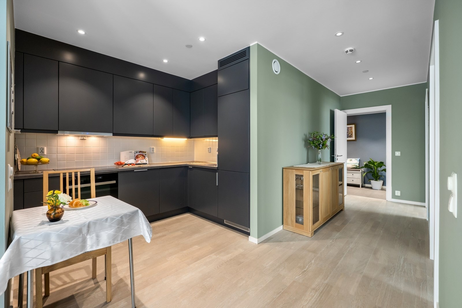 Moderne kjøkkeninnredning med mørke glatte fronter for et stilrent uttrykk. Det er donwlights som gir en behagelig belysning. Galleribilde