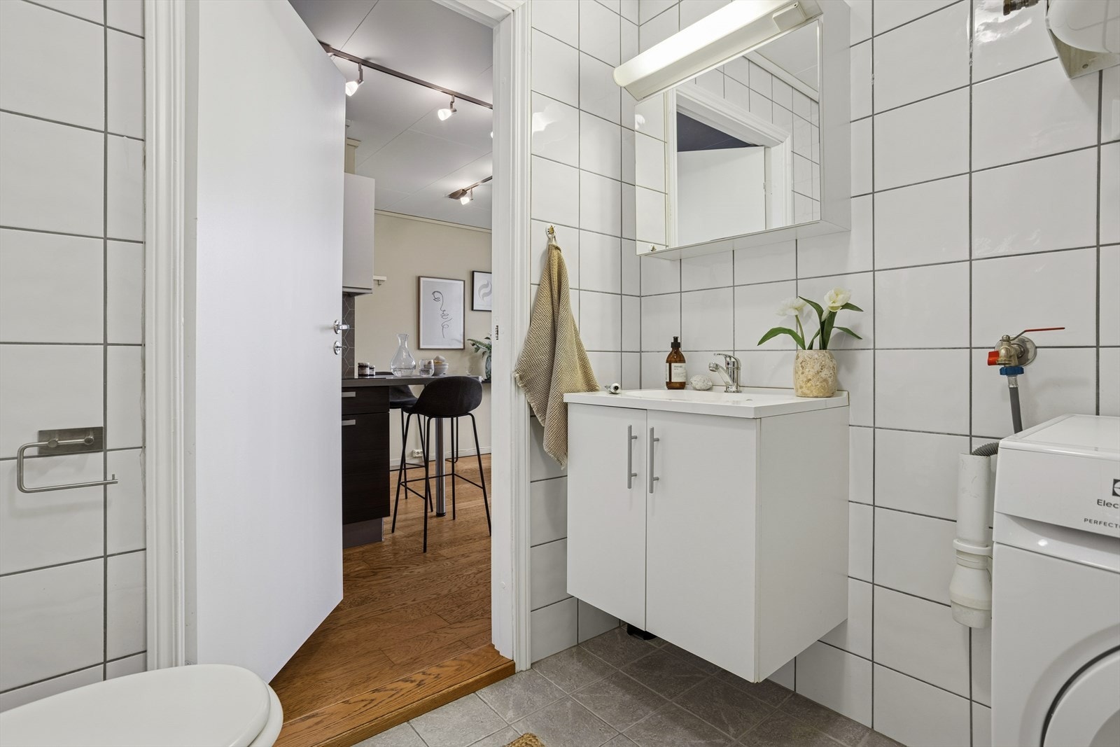 Baderomsinnredning med lagringsrom og et speil med belysning gjør badet både praktisk og elegant. Flislagt gulv med varmekabler sørger for komfort året rundt. Galleribilde