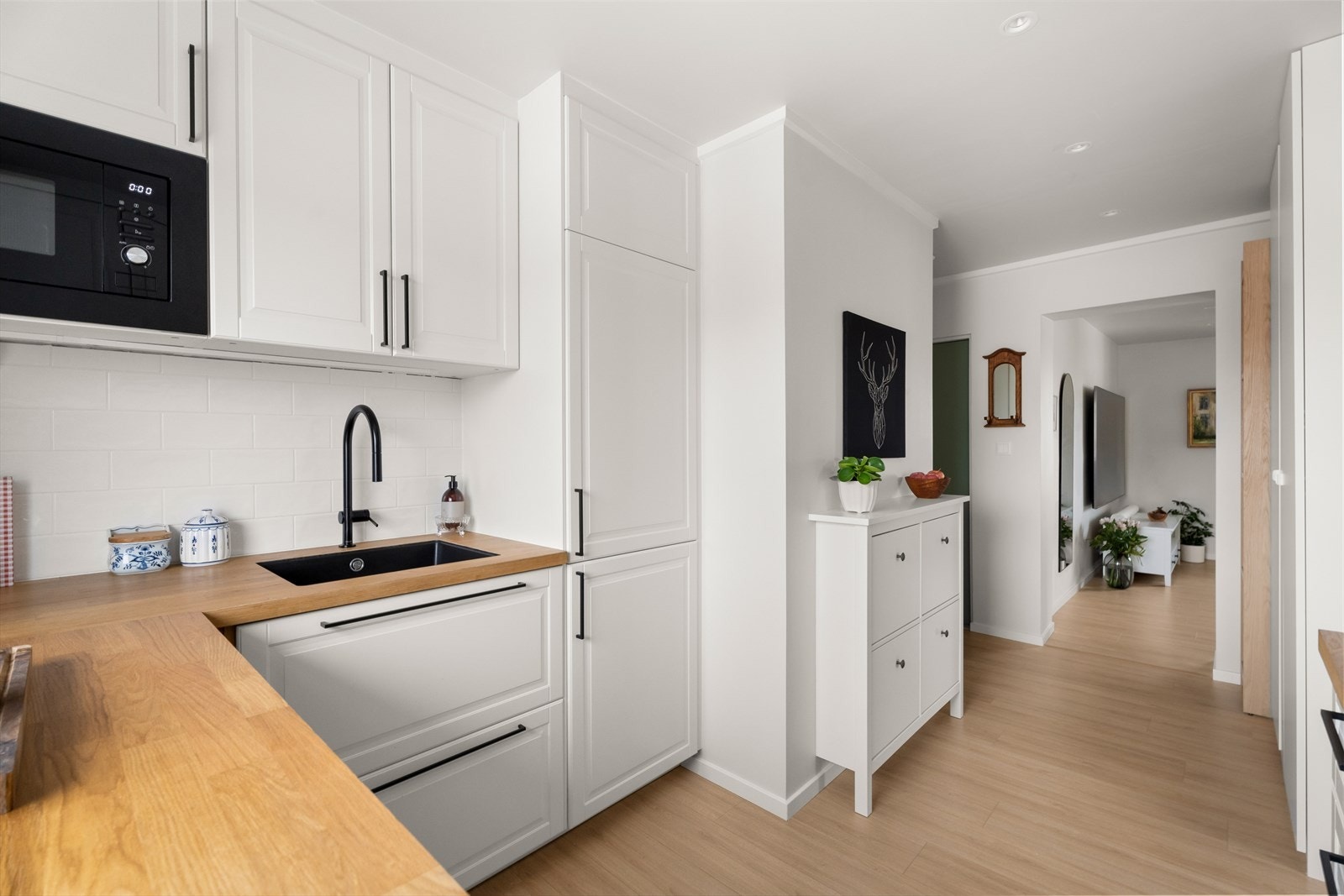 Kjøkkenet fra 2024 er en Ikea-innredning med lyse, profilerte fronter og en benkeplate i eikefinér med underlimt vask. Galleribilde