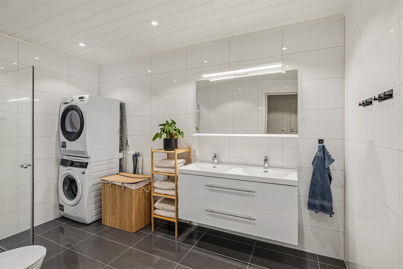 Badet har flislagte overflater på både vegger og gulv, med formpresset panel og downlights i himlingen. 30X60 Grå glossy fliser på gulv og 30x60 Glossy hvite fliser på vegger. Galleribilde