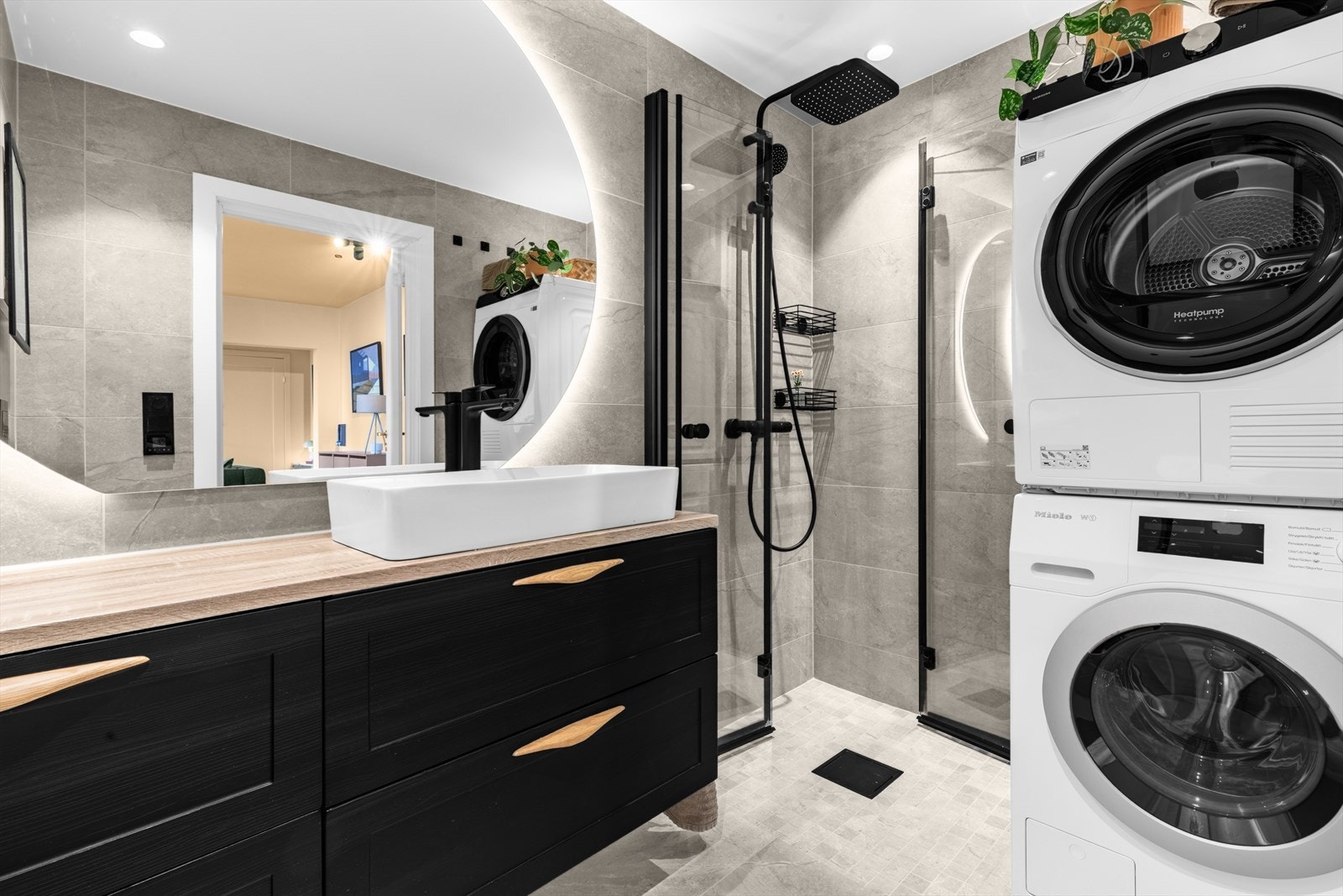 Romslig dusjsone med innfellbare dusjdører som gir en plassbesparende løsning. Det er også plass til både vaskemaskin og tørketrommel, noe som gjør badet svært funksjonelt i hverdagen. Galleribilde