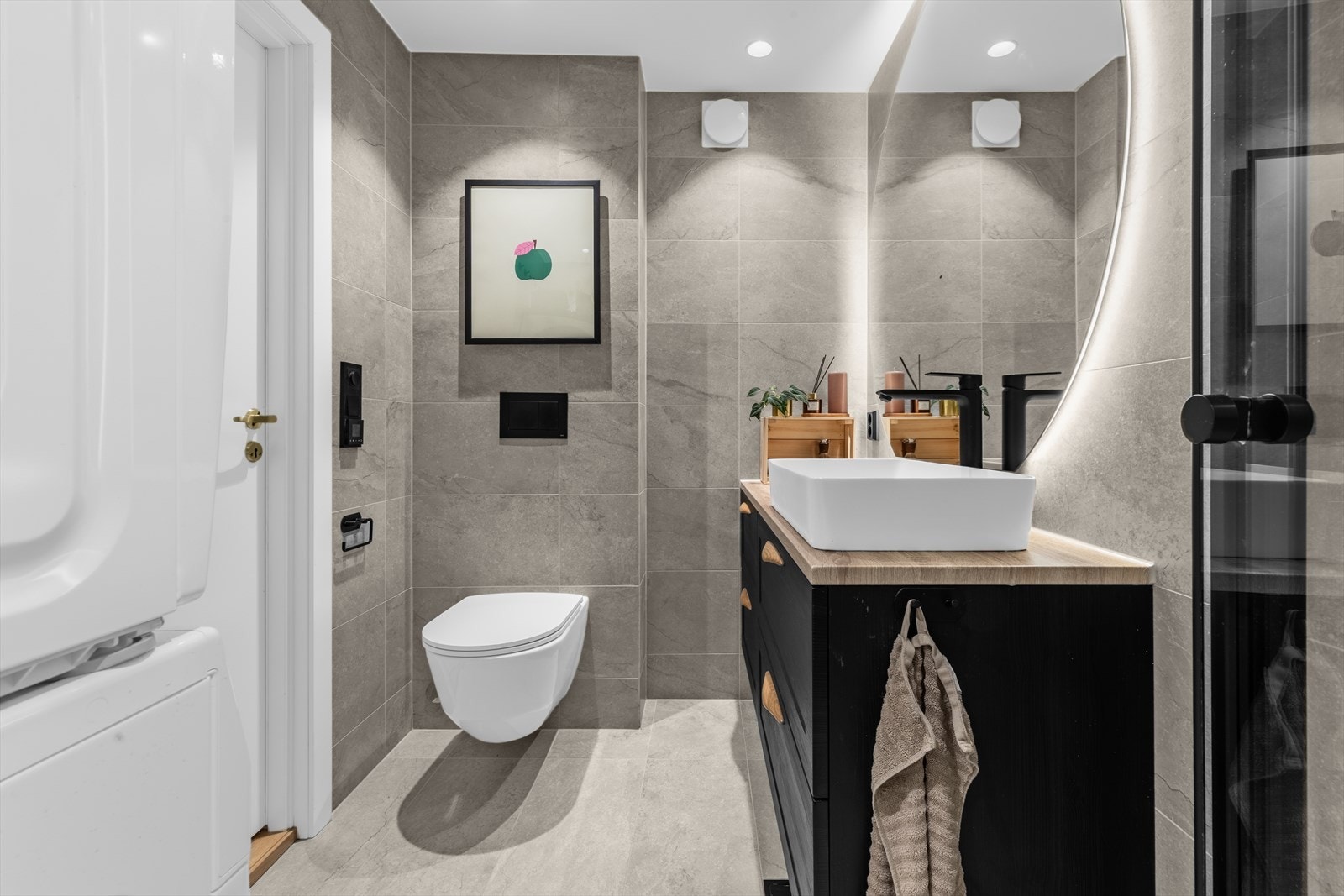 Den sorte baderomsinnredningen med treverkdetaljer gir rommet et eksusivt preg, og det store speilet med integrert lys gjør rommet ekstra innbydende. Galleribilde