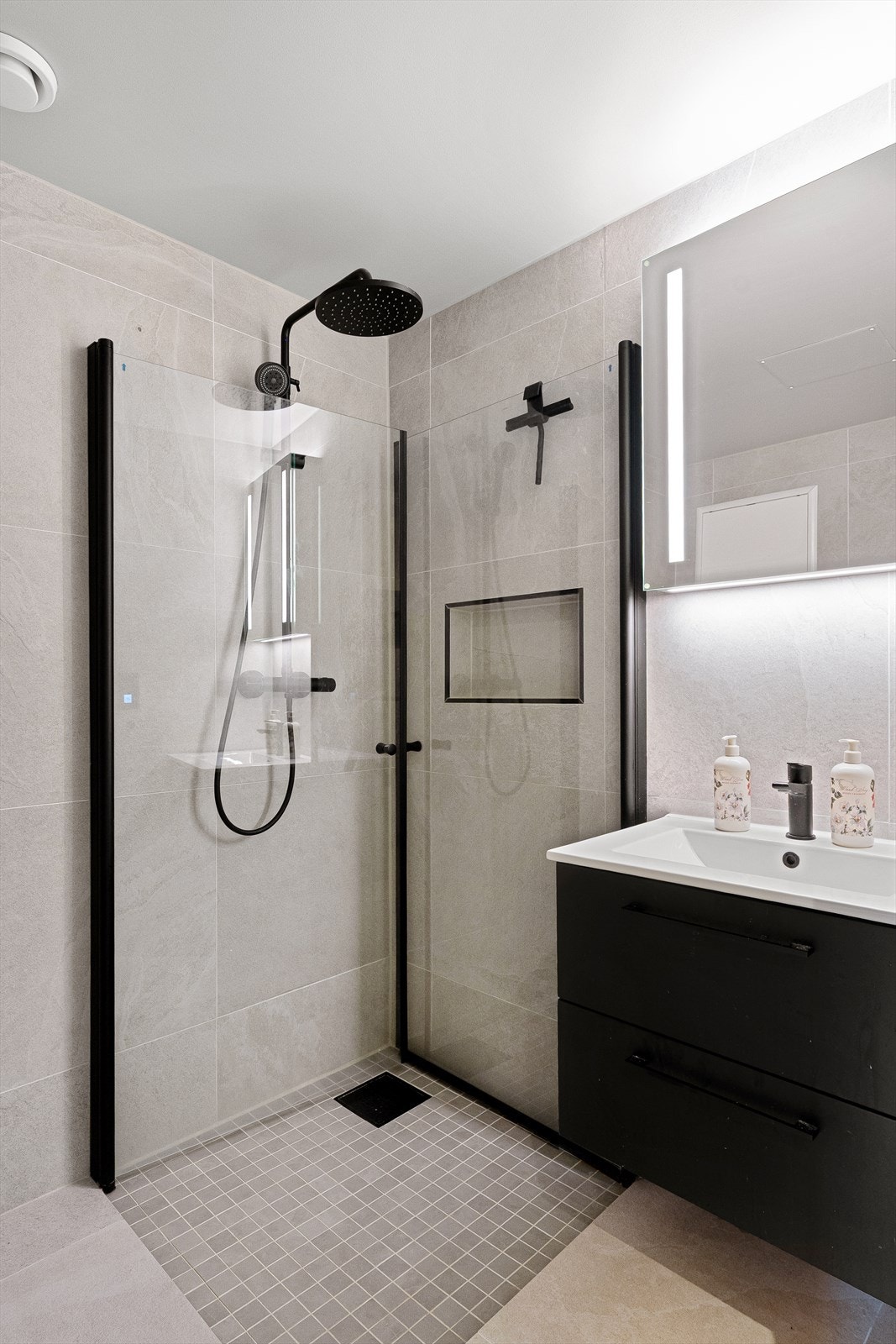 Ellers er badet innredet med seksjon med servant, speil med belysning, dusjhjørne og vegghengt toalett. Galleribilde