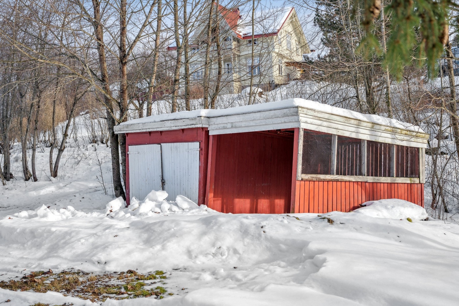 På eiendommen står det en frittstående, rødmalt garasjebygning oppført med en todelt løsning. Galleribilde