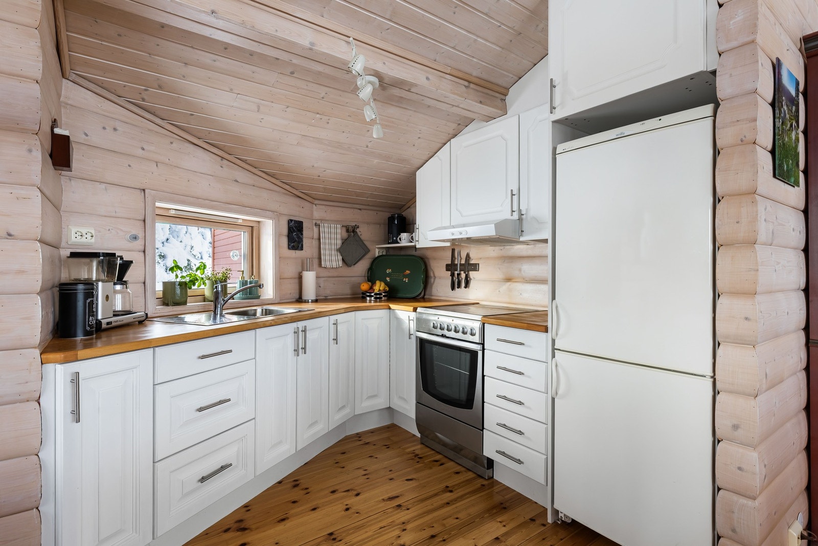 Koselig kjøkken med frittstående hvitevarer og benkeplate i tre. Galleribilde