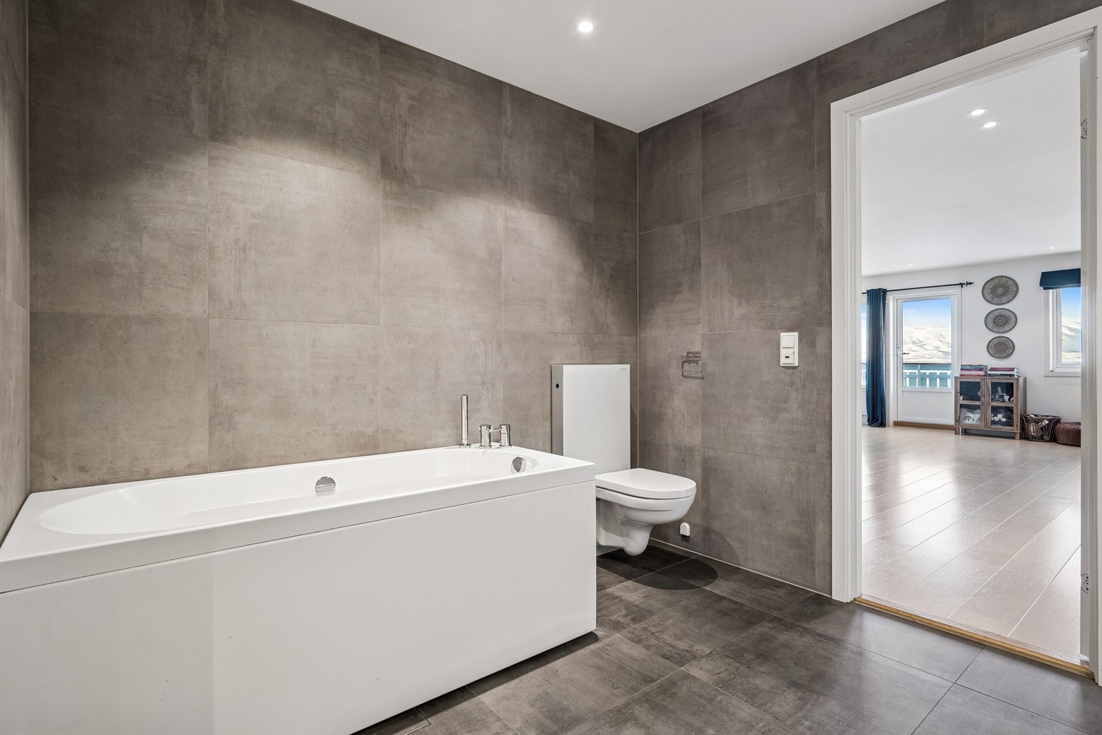 Badet er utstyrt med badekar, vegghengt innredning og toalett i tillegg til vaskemaksin og tørketrommel Galleribilde