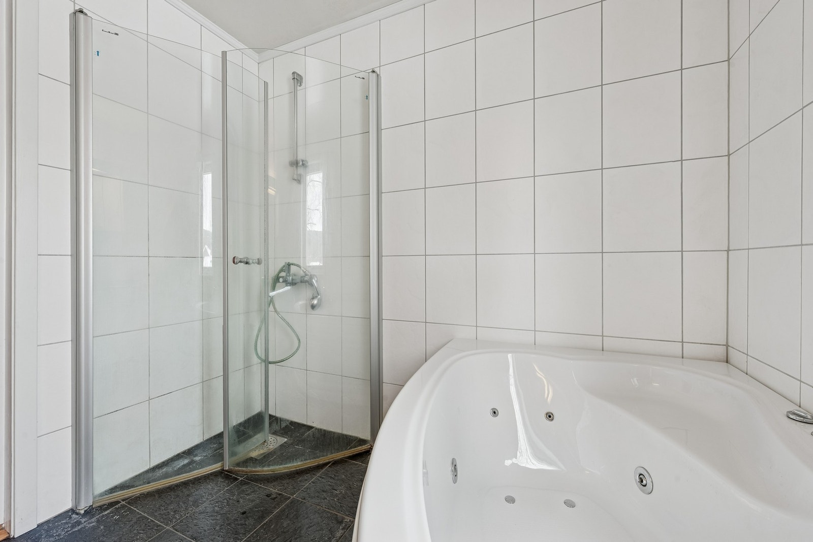 Badet er innredet med servant i innredning, badekar, innfellbare dusjdører og klosett. Galleribilde