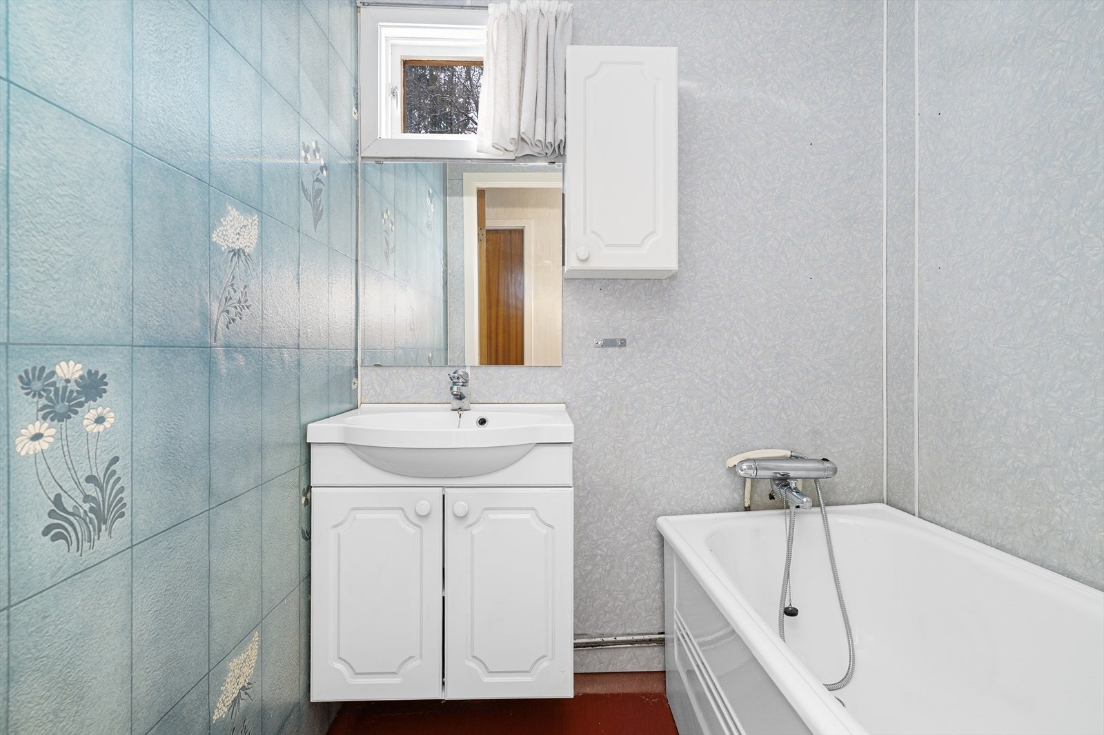 Badet og toalettrommet har en praktisk plassering i boligen, inntil soverommene. Badet er av eldre dato, med belegg på gulvet og innredet med servantskap, speil og overskap, samt badekar. Galleribilde