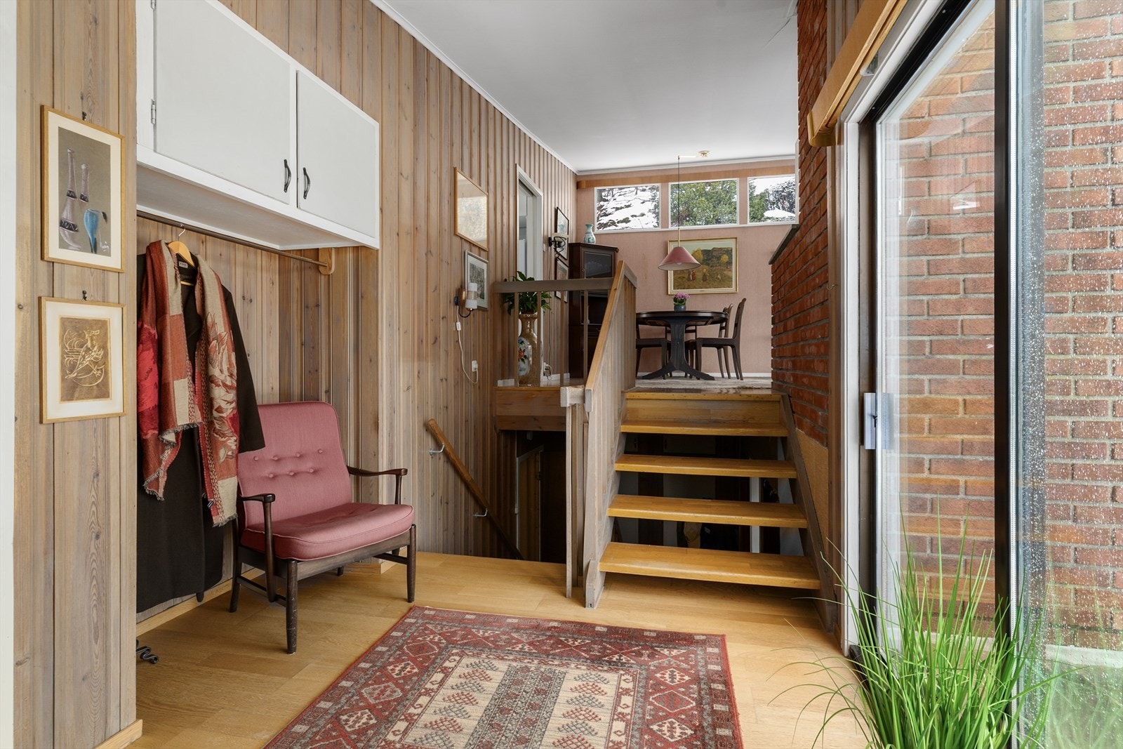 Hallen har en liten nisje for klesoppbevaring, med garderobestang og overskap. Fra hallen er det terrassedør med utgang til den usjenerte og koselige hagen hvor det bl.a. er opparbeidet skiferlagt uteområde. Galleribilde