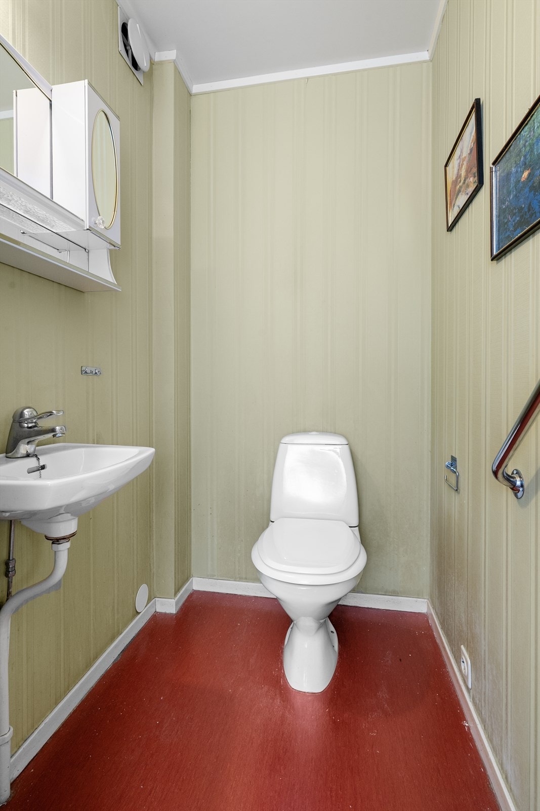 Toalettrommet ligger inntil badet og er innredet med vaskeservant og toalett. Overflater er belegg på gulvet og tapet på veggene. Galleribilde