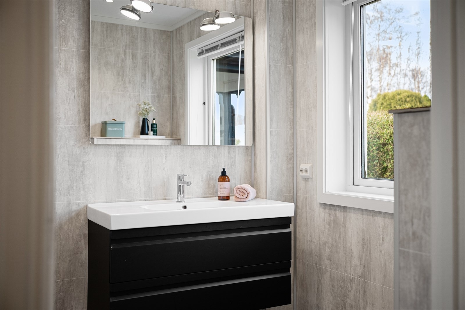 Sort seksjon med servant og speil. Rommet har varme i gulvet for ekstra komfort. Galleribilde