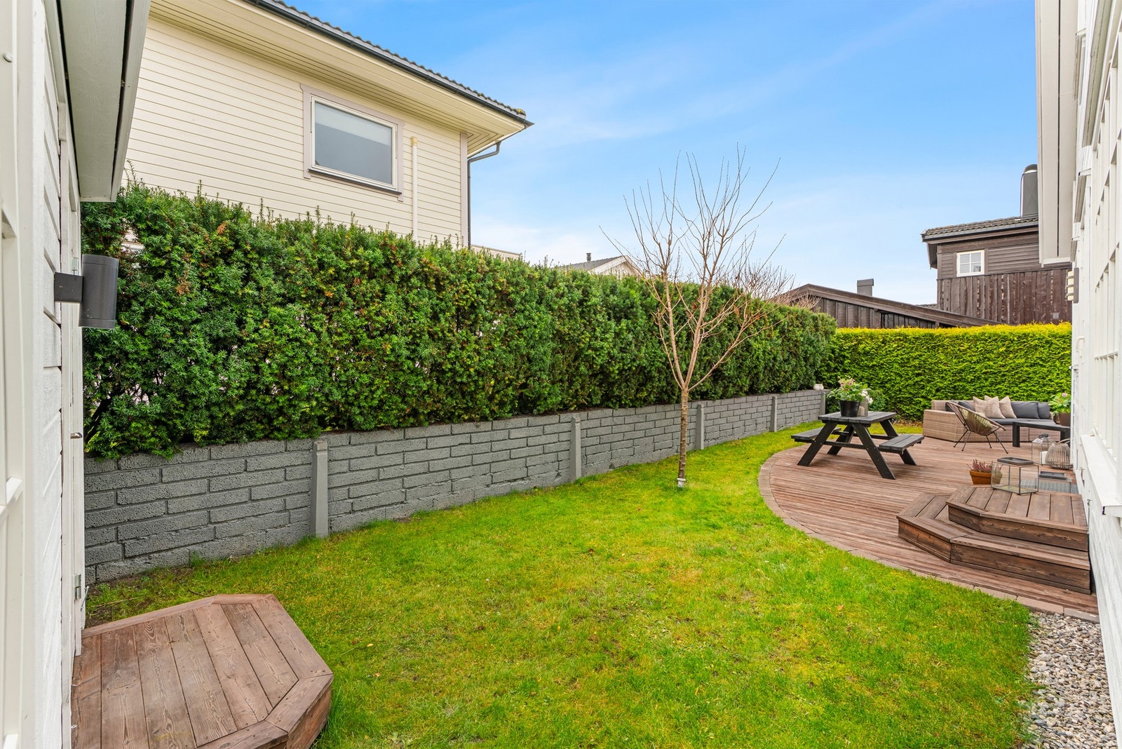 Hagen er pent opparbeidet med gressplen, fine beplantninger, skjermende hekk, prydbusker, trær og sensorstyrt utelys Galleribilde