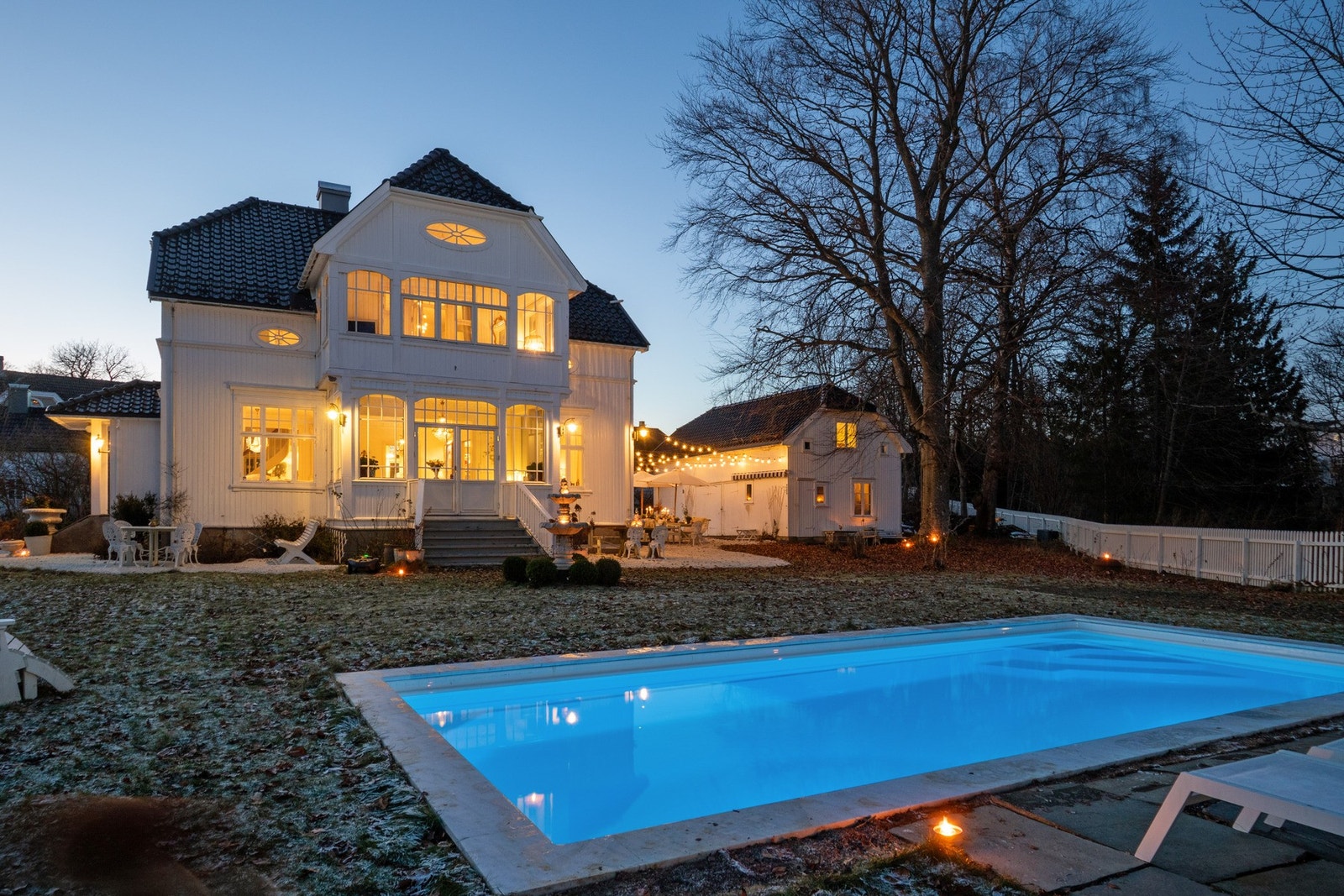 Stemningsfull kveld i hagen, hvor lysene fra villaen og uteplassen skaper en helt spesiell atmosfære. Galleribilde