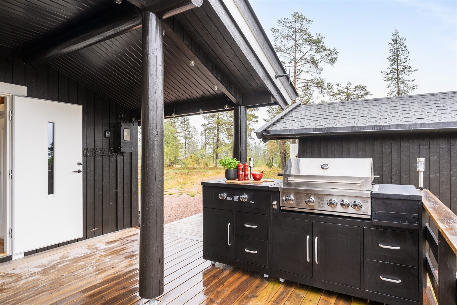 Inngang via dels overbygget terrasse av tre med rekkverk og utekjøkken. Galleribilde