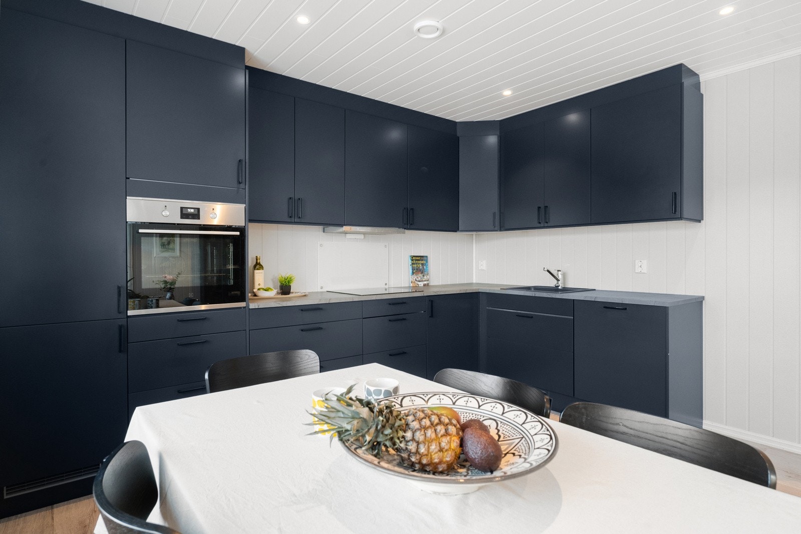 Det stilrene Norema-kjøkkenet med mørke, glatte fronter danner en elegant ramme rundt rommet og er utstyrt med integrerte hvitevarer fra Electrolux. Galleribilde